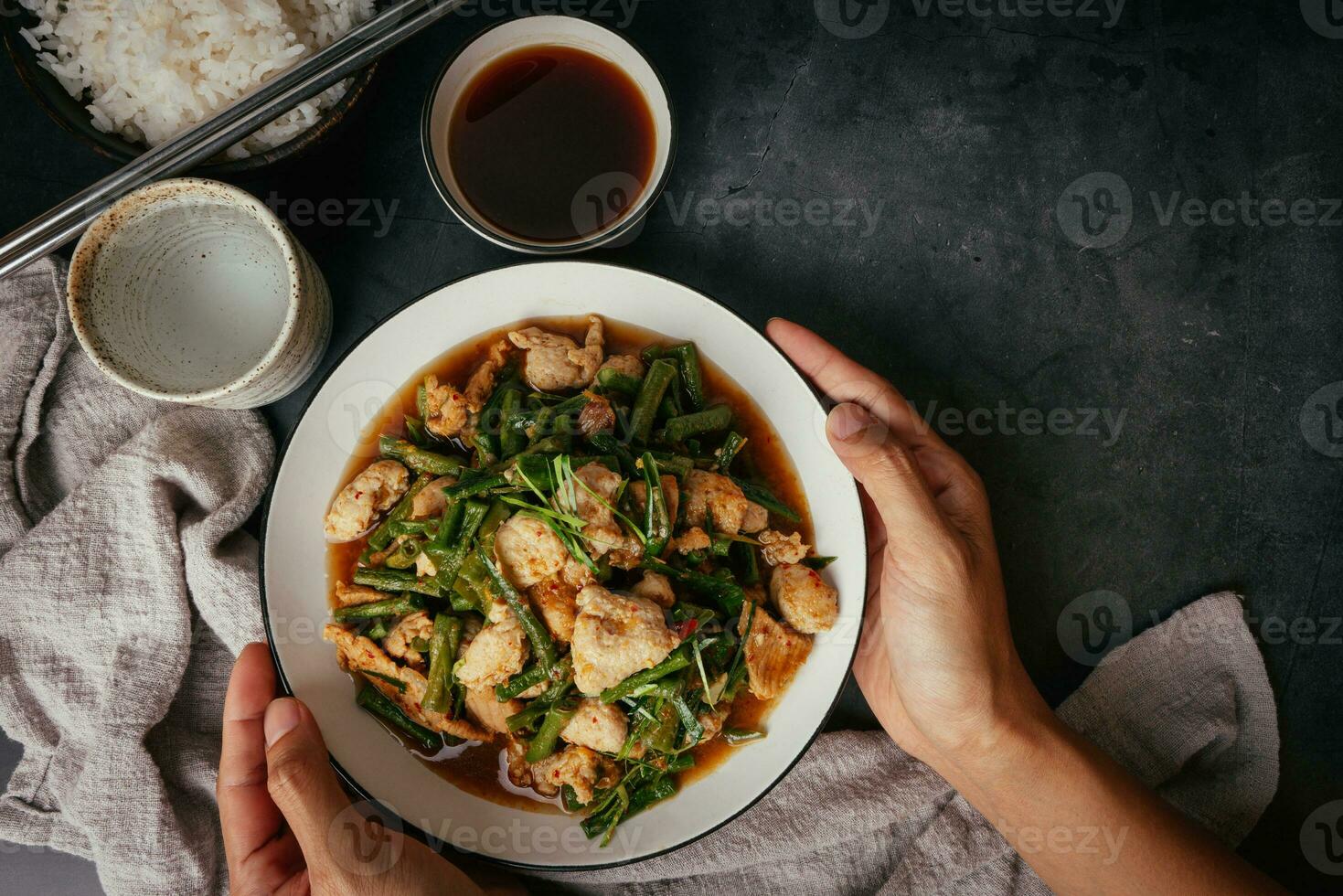 Hand-serving of delicious long bean Stir-fried pork and red hot curry paste with Ingredients of oyster sauce, fish sauce, sugar, kaffir lime leaves in the dish Eat with cooked rice. Thai cuisine photo