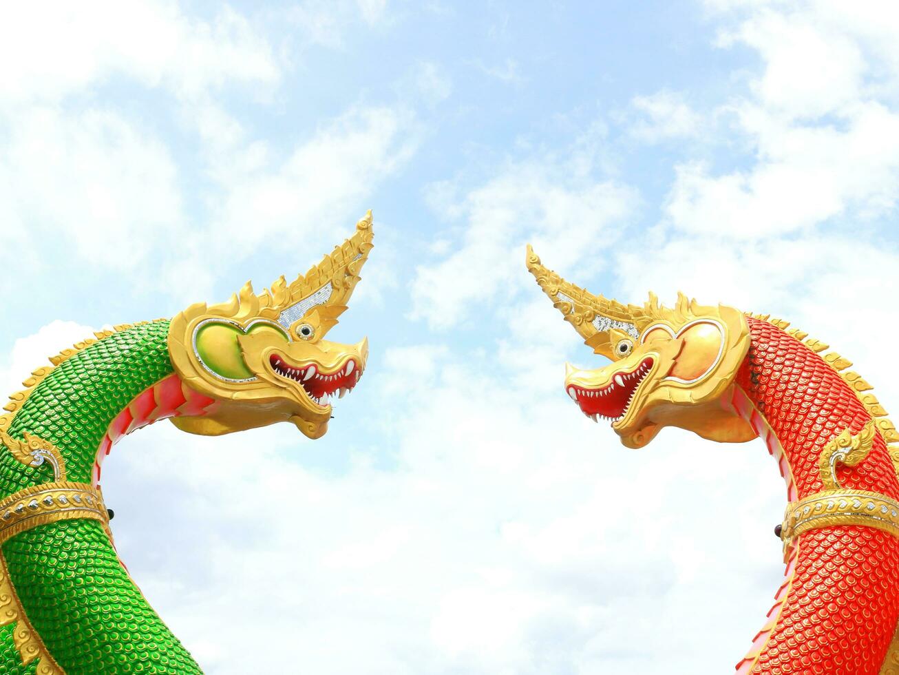 Two serpent red and green color Thai style statue, face to face posture and blue sky with white cloud, Thailand. photo