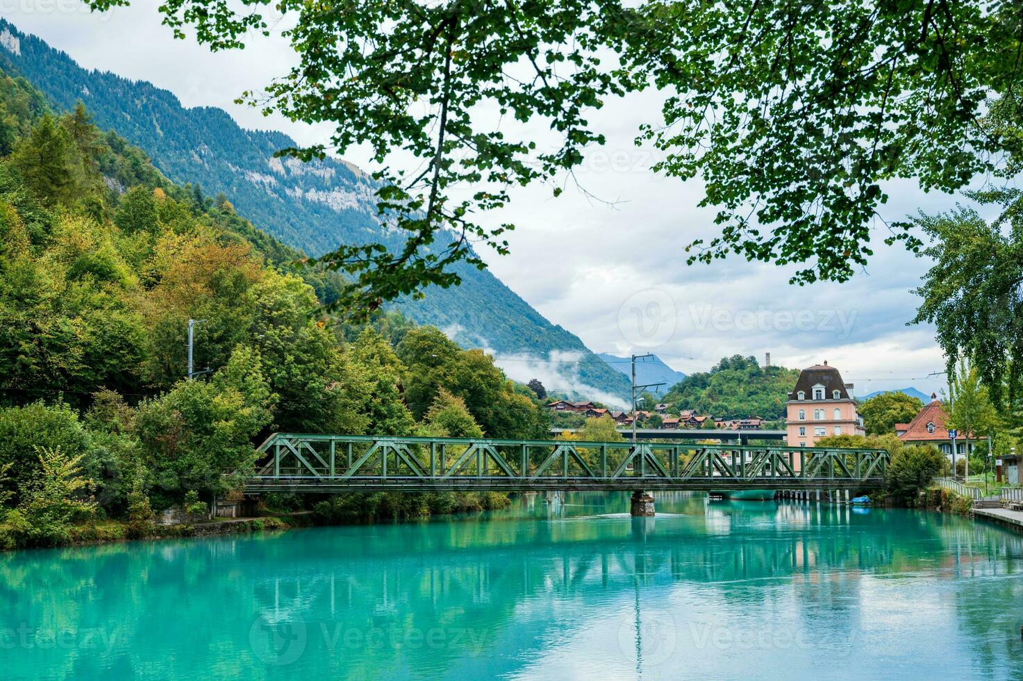 A beautiful emerald green river that is so clear that it reflects the sky and scenery. In Interlaken, Switzerland, the Aare River with natural water sources flowing down from high mountains. photo