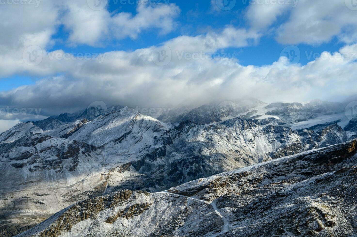 Panoramic view of towering mountains of Gornergrat covered with snow and clouds on a clear day. It is an image that shows the beauty of great nature suitable to attract tourists to visit uninterrupted photo
