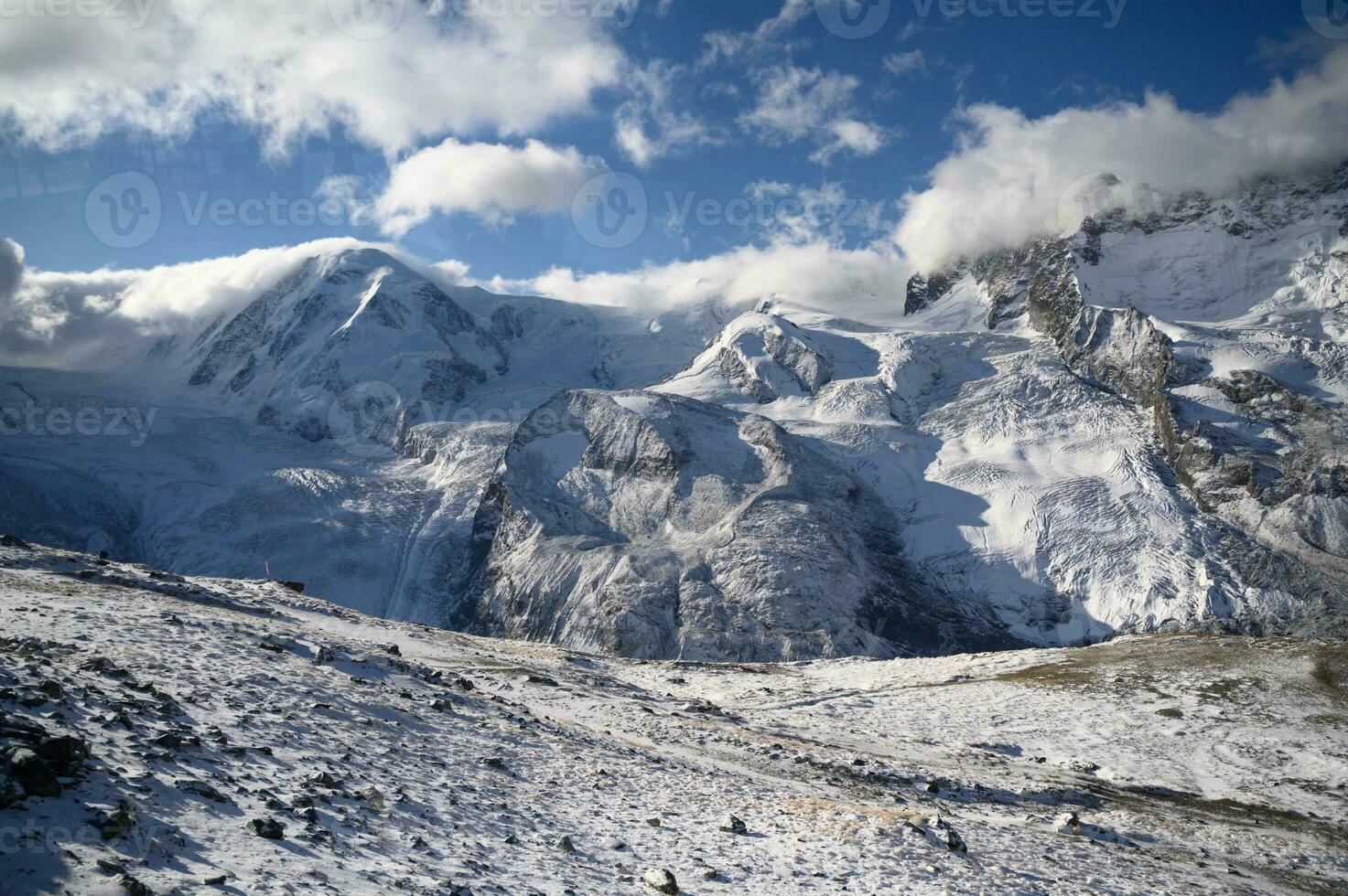 Panoramic view of towering mountains of Gornergrat covered with snow and clouds on a clear day. It is an image that shows the beauty of great nature suitable to attract tourists to visit uninterrupted photo