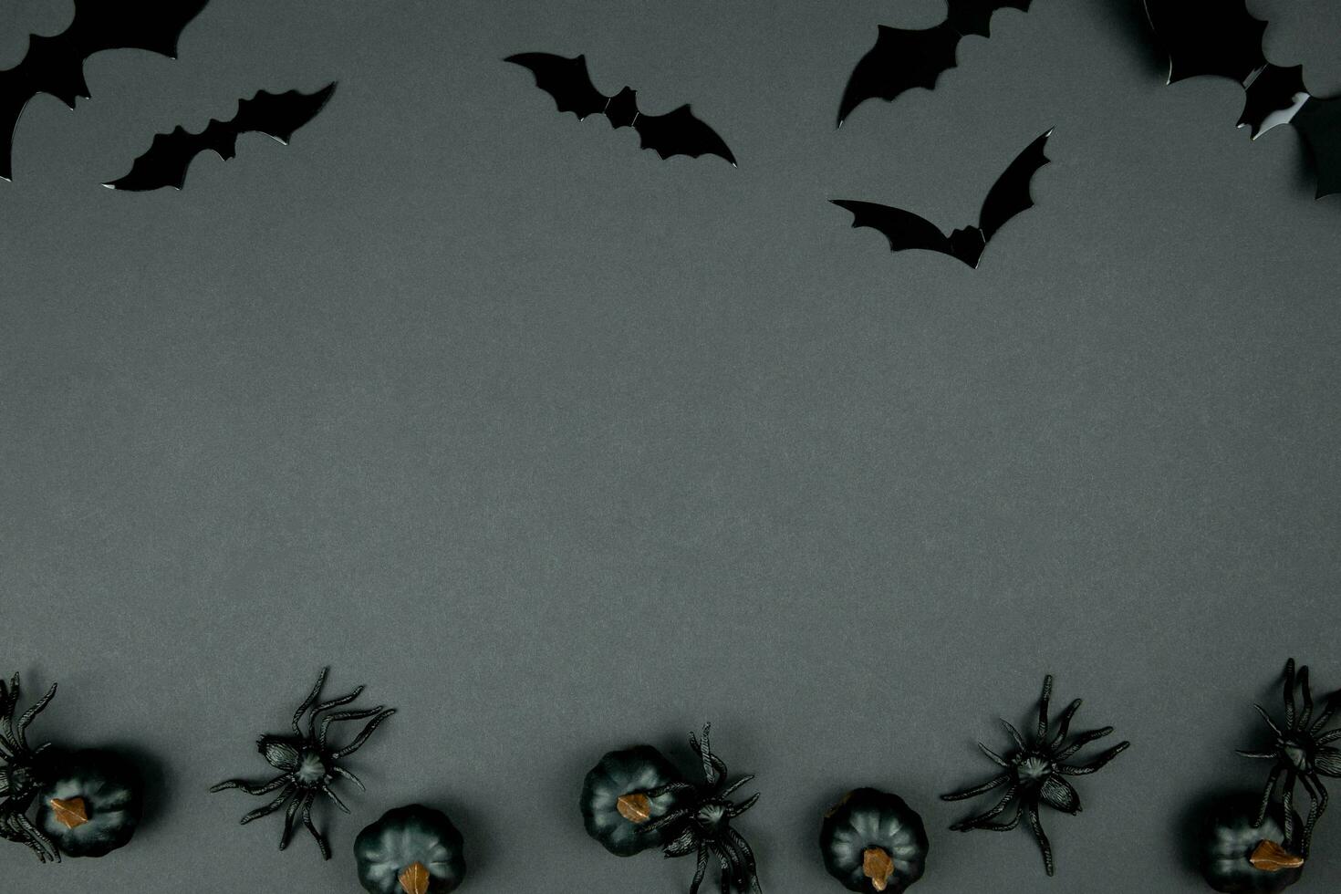 Happy halloween flat lay composition with black pumpkins, spiders and bats on dark background. Holiday concept. Top view. Copy space. photo