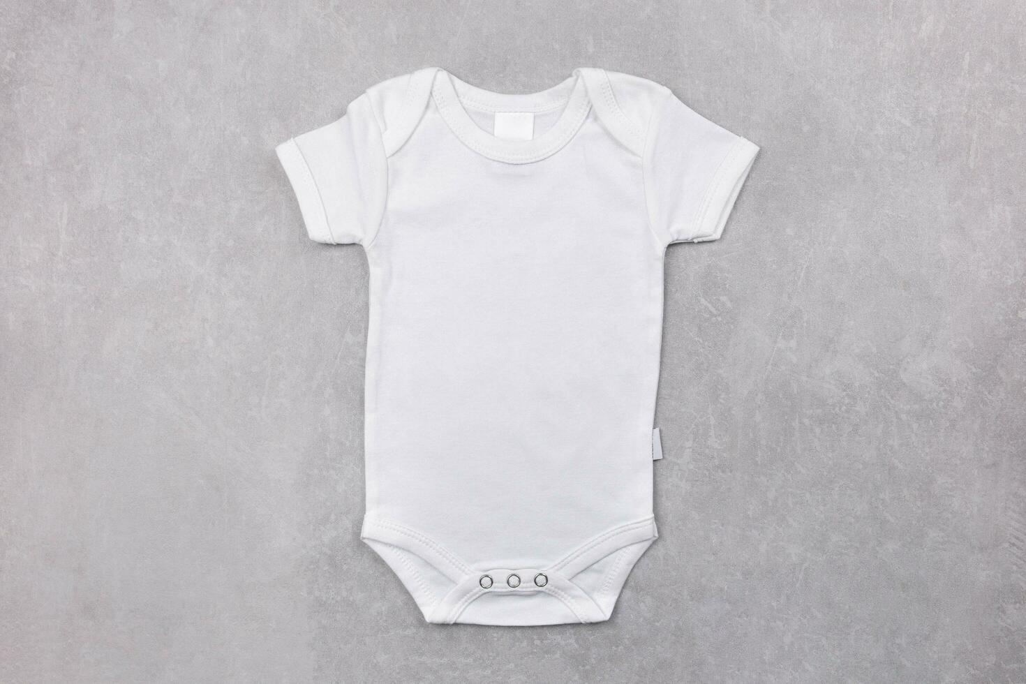 White baby girl or boy bodysuit mockup flat lay on the gray concrete background. Design onesie template, print presentation mock up. Top view. photo