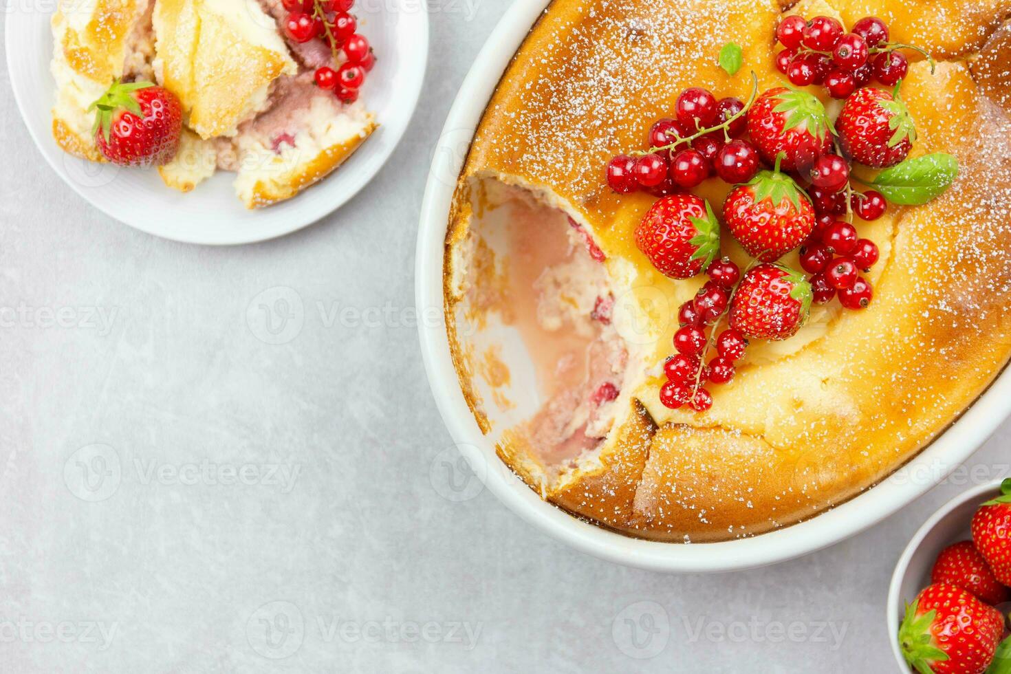 Homemade casserole with cottage cheese, semolina, fresh red currant berries and strawberry on light gray background. Top view. Copy space. Close up. photo