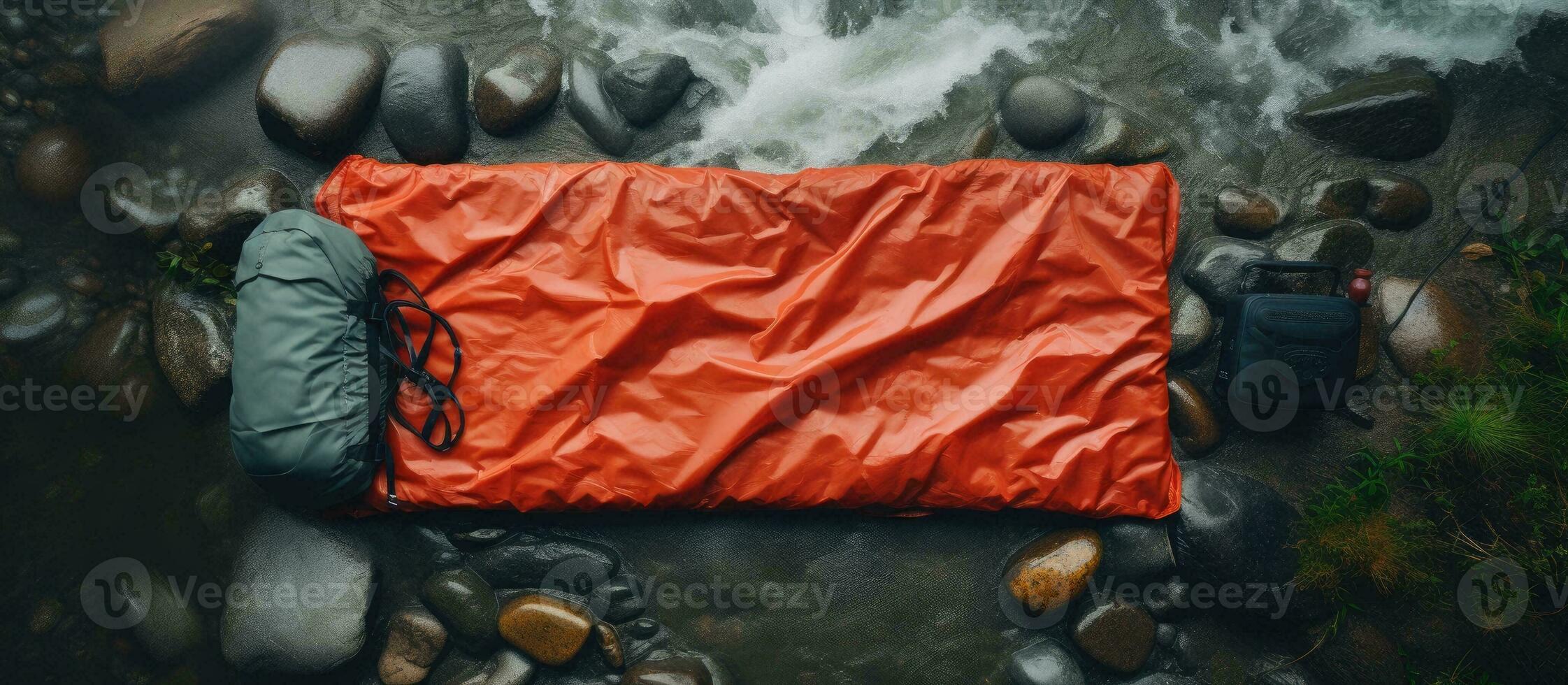 Photo of an orange sleeping bag on a rocky beach, with plenty of space for relaxation and solitude with copy space