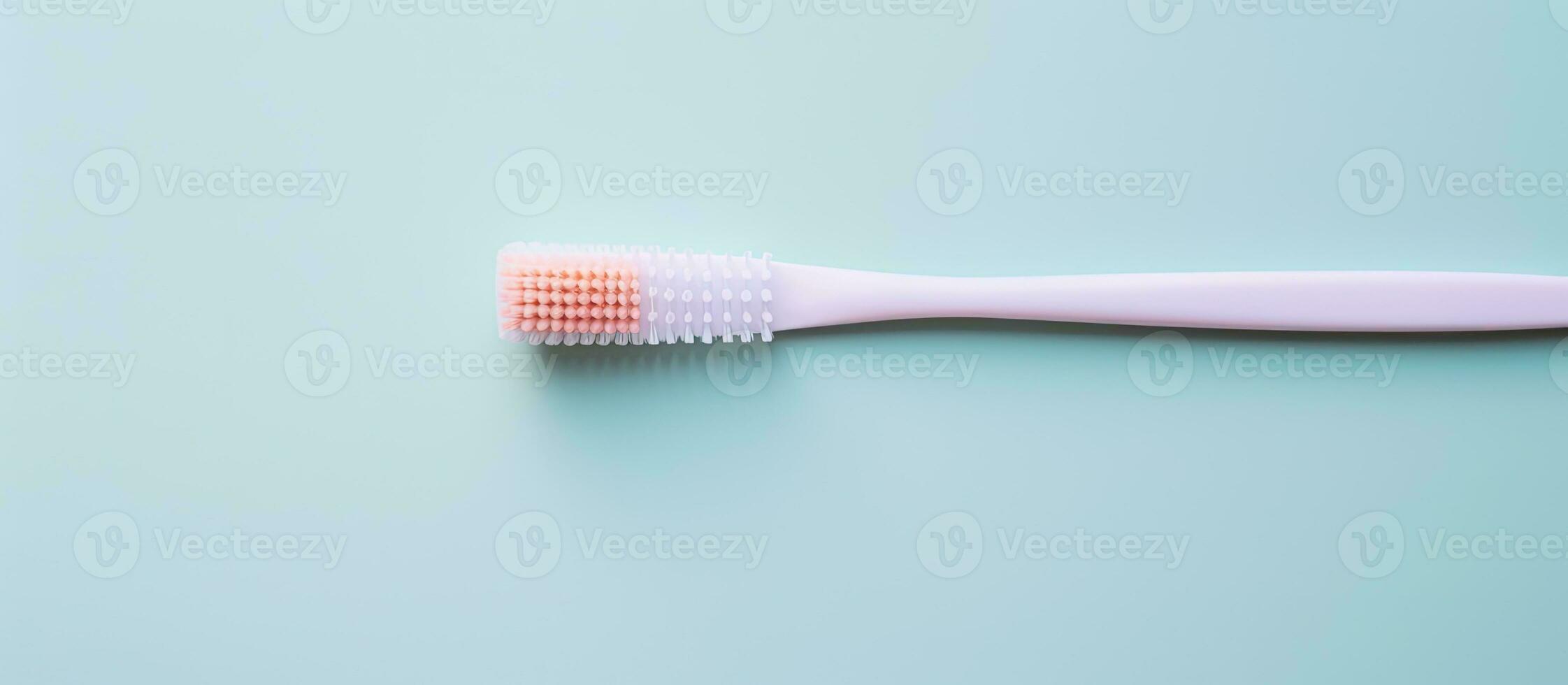 Photo of a pink toothbrush on a blue surface with copy space