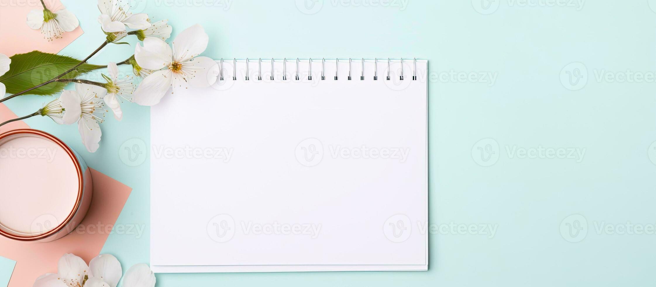 Photo of a cup of coffee, notepad, and flower on a blue background with copy space with copy space