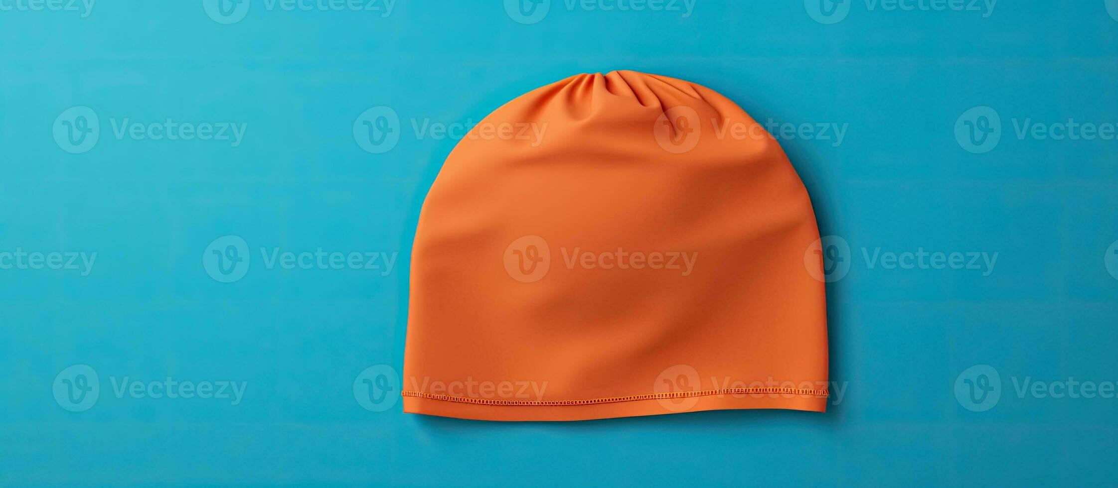 Photo of an orange beanie on a vibrant blue background with plenty of space for copy or text overlay with copy space
