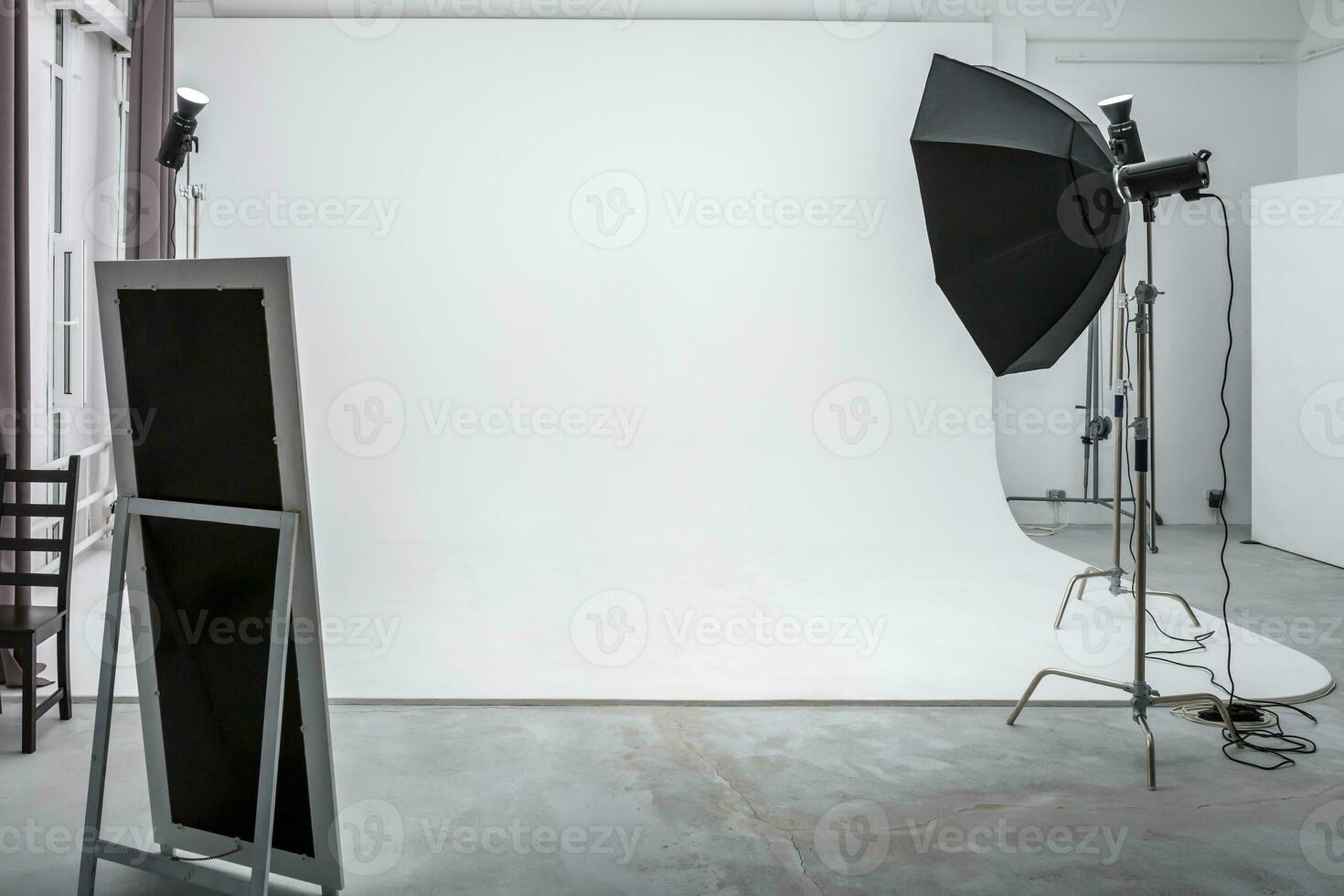 interior of bright space of photo studio with large white cyclorama with lighting equipment