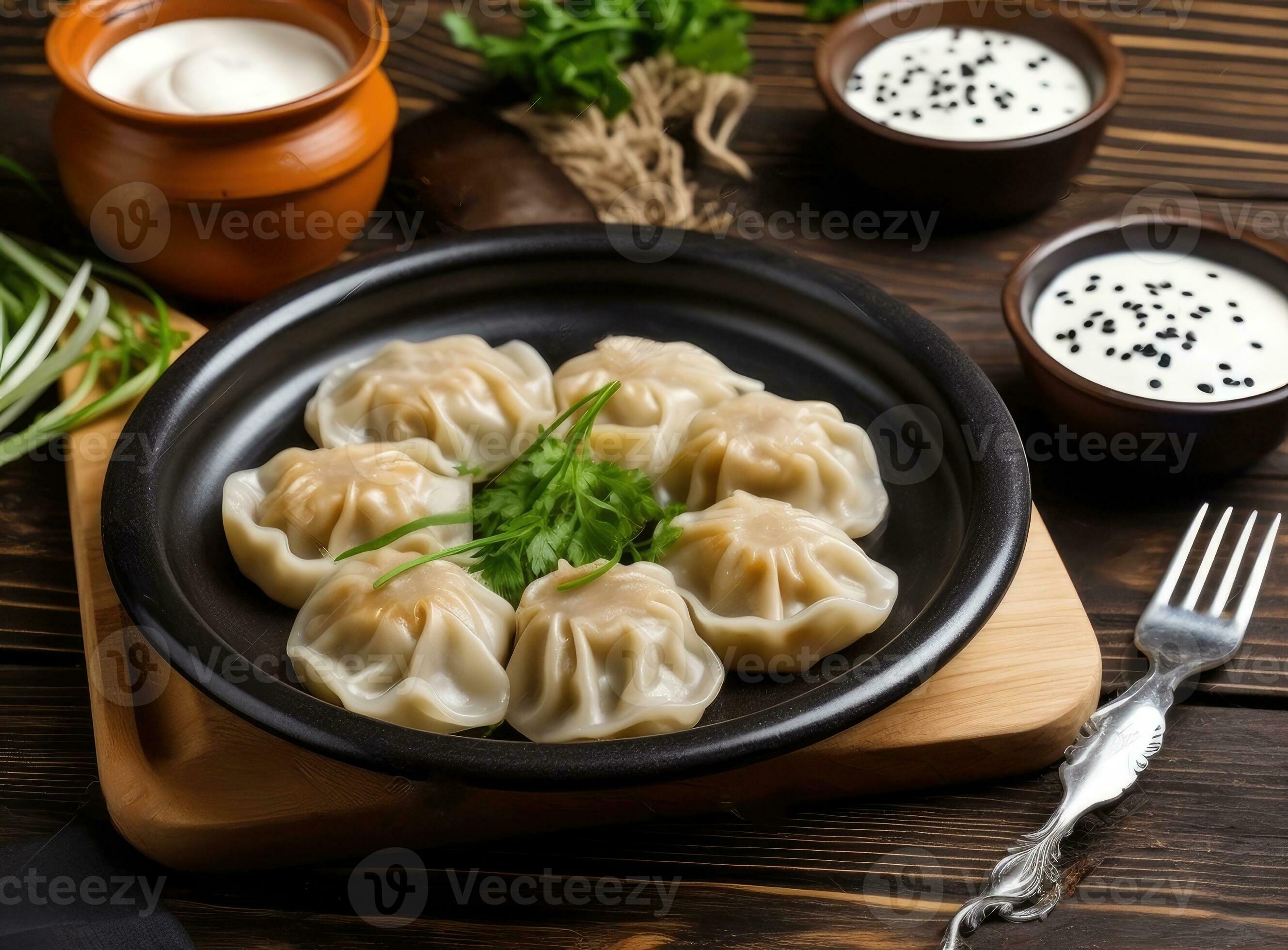Delicious cooked dumplings with sour cream on dark wooden table, flat