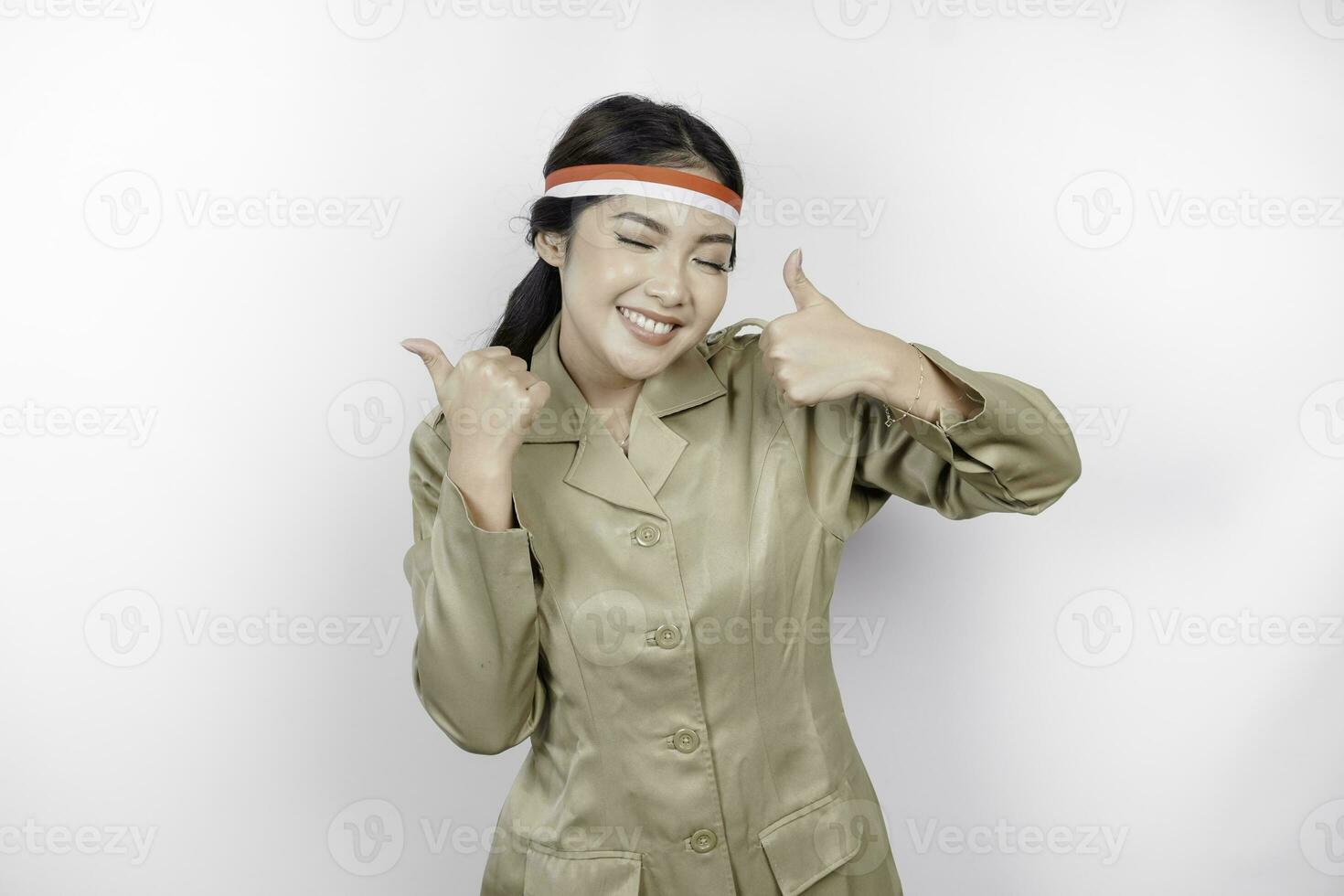 Smiling government worker woman gesturing OK sign with her thumbs up isolated by white background. PNS wearing khaki uniform. Indonesia's independence day concept. photo