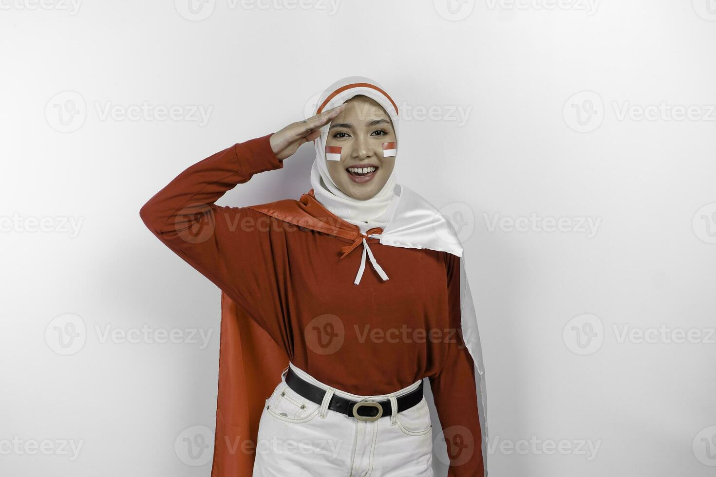 Indonesian muslim woman wearing hijab give salute with proud gesture while holding Indonesia's flag. Indonesia's independence day concept photo