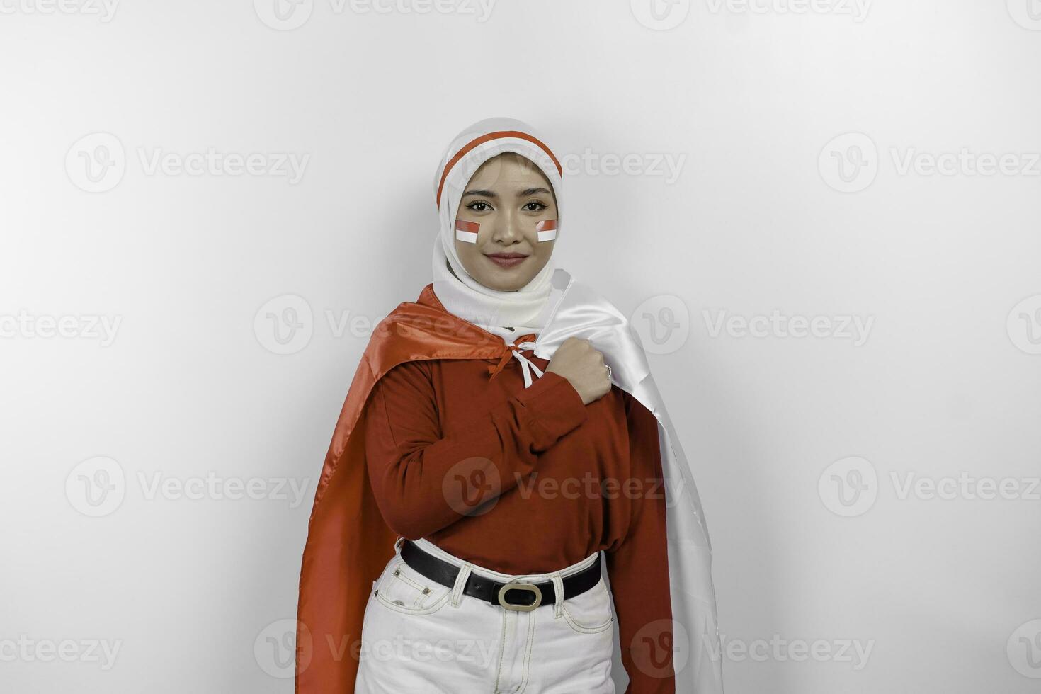 Indonesian muslim woman wearing hijab give salute with proud gesture while holding Indonesia's flag. Indonesia's independence day concept photo
