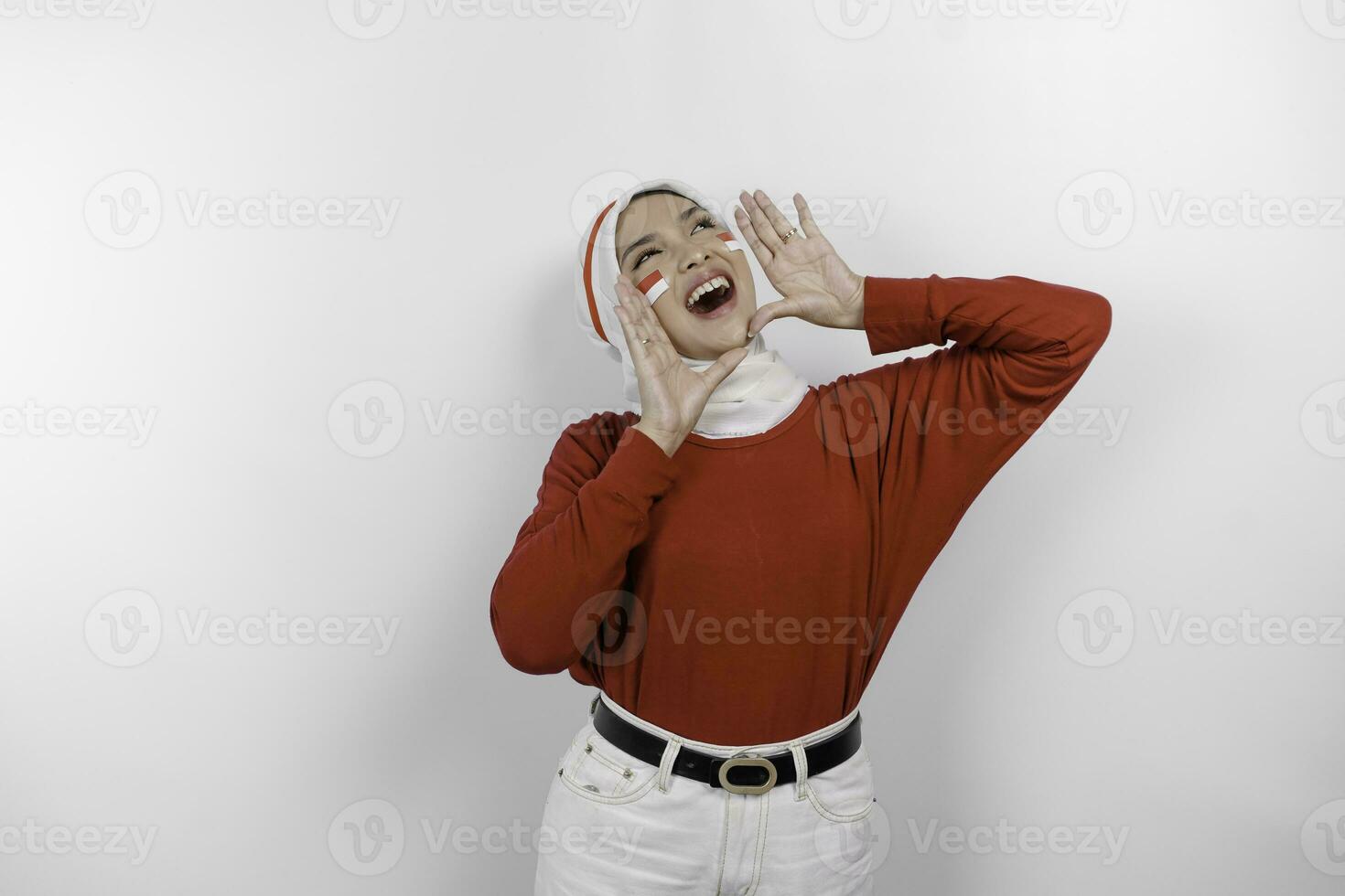 Young beautiful muslim woman wearing a red top and white hijab is shouting and screaming loud with a hand on her mouth. Indonesia's independence day concept. photo