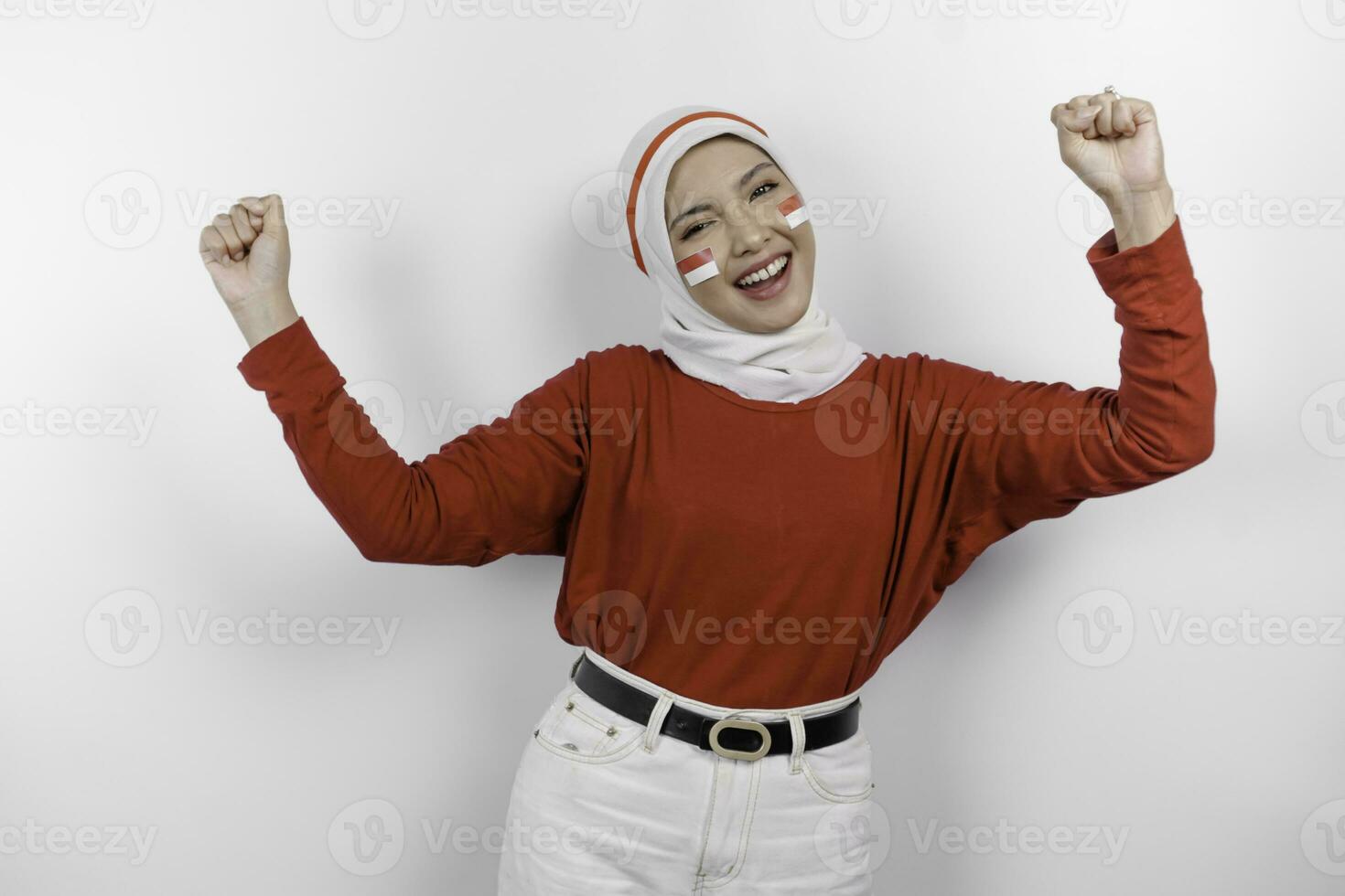 A young Asian muslim woman with a happy successful expression wearing red top and white hijab isolated by white background. Indonesia's independence day concept. photo