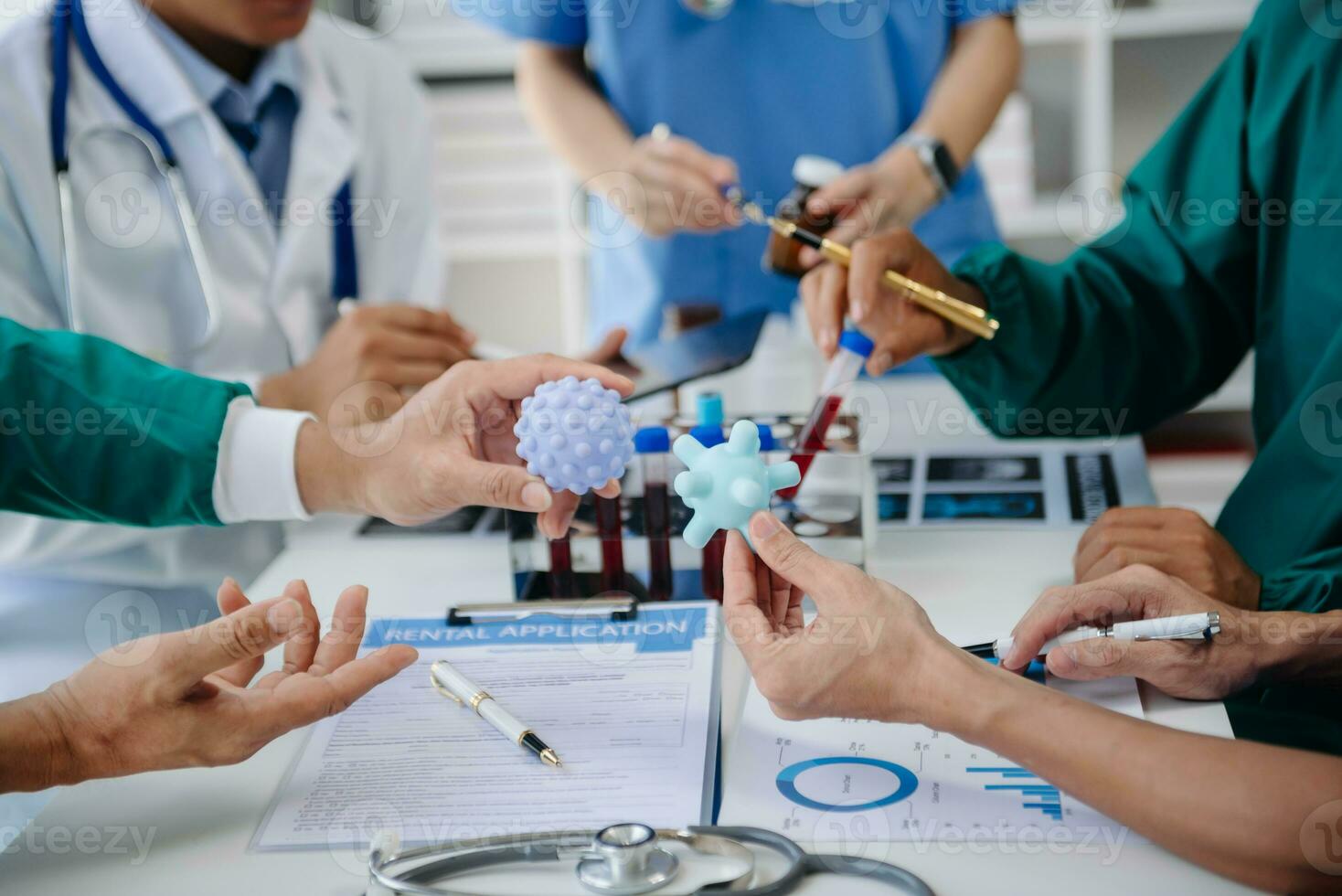 Medical team having a meeting with doctors in white lab coats and surgical scrubs seated at a table discussing a patients working online using computers in the medical industry photo