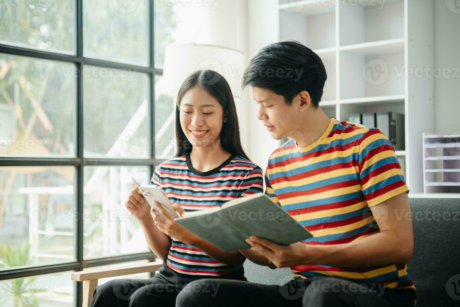 Two asian students learning together online with a laptop, tablet and tutor together in living room at home. photo