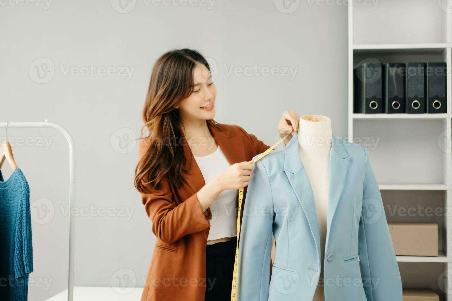 Successful fashion designer. Attractive young asian woman with smile while standing in workshop. Beautiful owner business woman working and holds tablet, laptop and smartphone in studio. photo