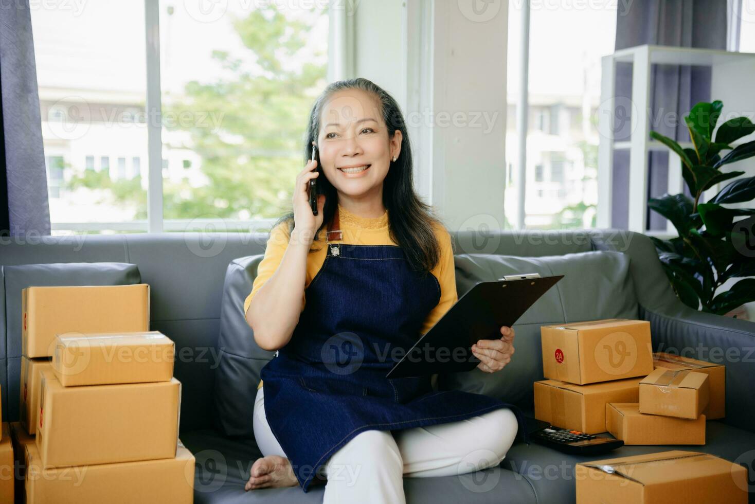 Mature business owner woman prepare parcel box and standing check online orders for deliver to customer on tablet, laptop Shopping Online photo