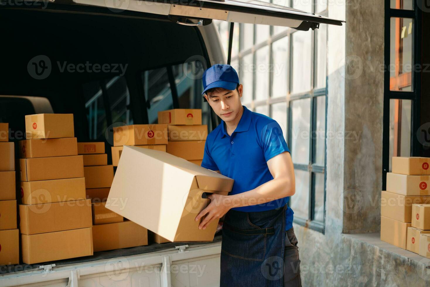 Smiling delivery man standing in front of his van with Holding Box and tablet delivery home and shipping photo