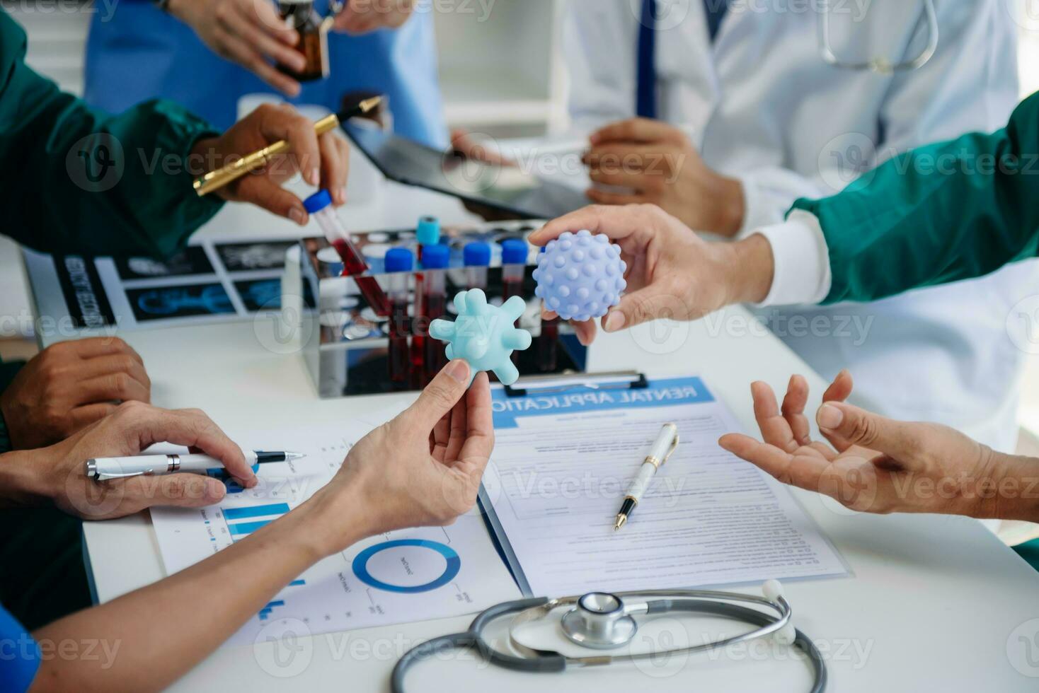 Medical team having a meeting with doctors in white lab coats and surgical scrubs seated at a table discussing a patients working online using computers in the medical industry photo