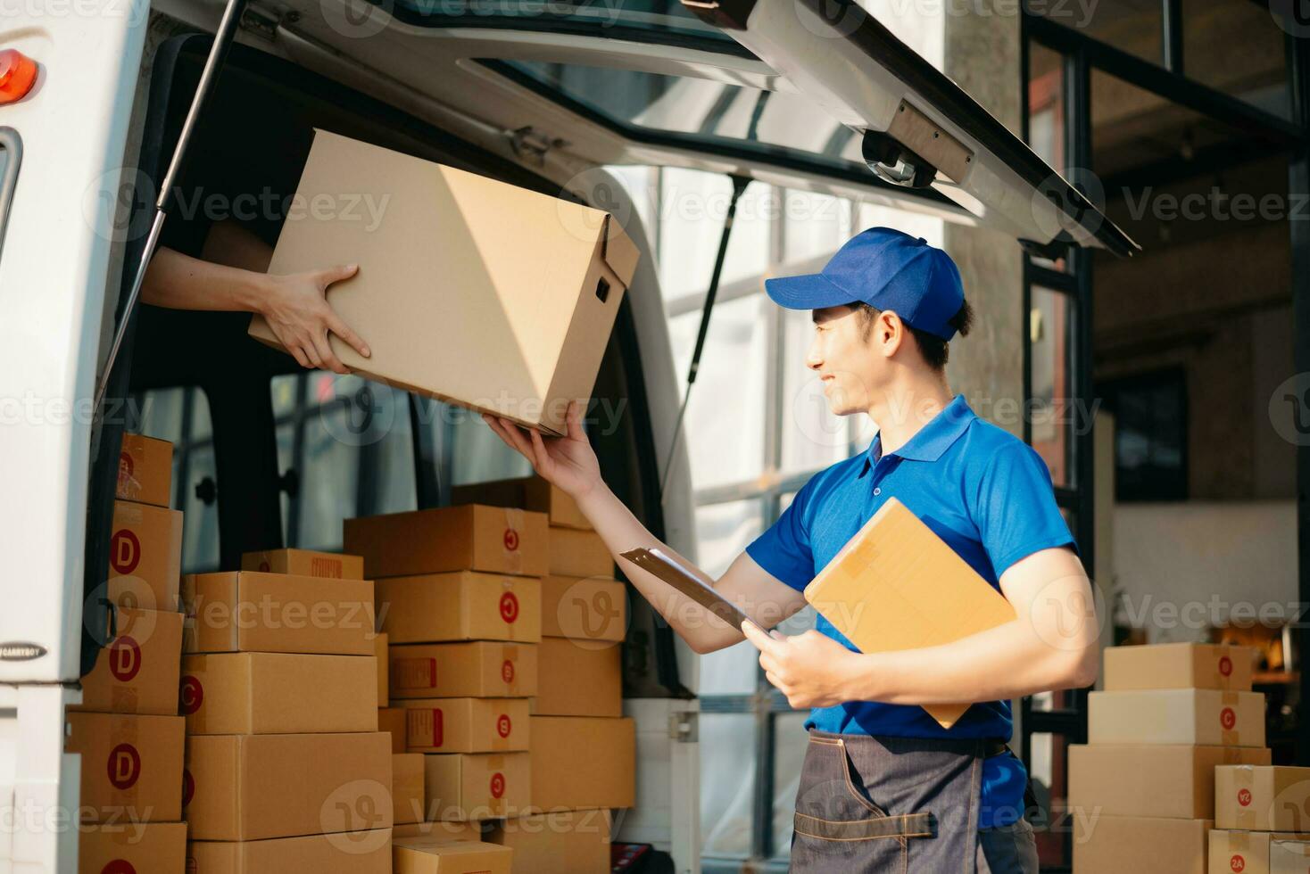 Smiling delivery man standing in front of his van with Holding Box and tablet delivery home and shipping photo
