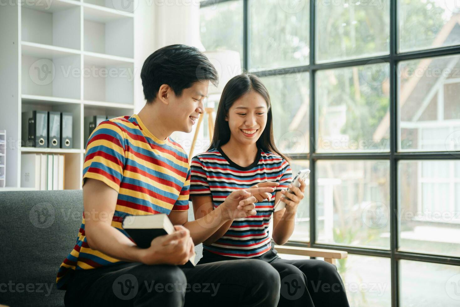 Two asian students learning together online with a laptop, tablet and tutor together in living room at home. photo