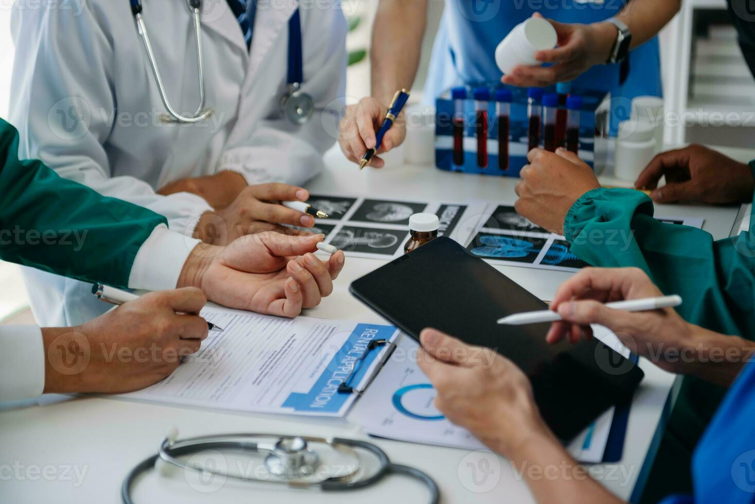 Medical team having a meeting with doctors in white lab coats and surgical scrubs seated at a table discussing a patients working online using computers in the medical industry photo