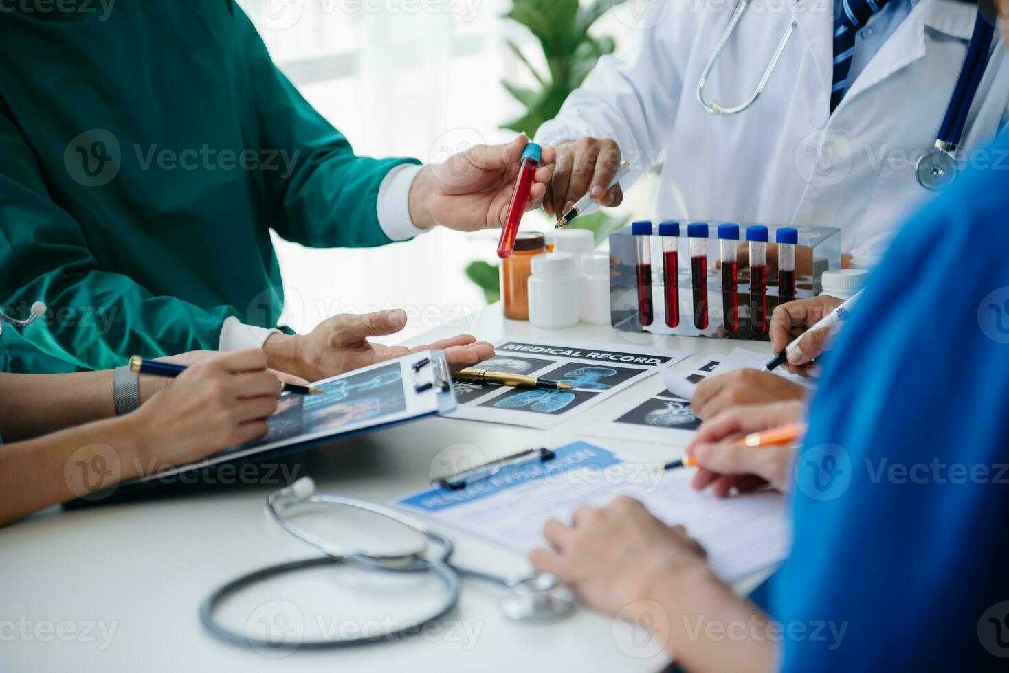 Medical team having a meeting with doctors in white lab coats and surgical scrubs seated at a table discussing a patients working online using computers in the medical industry photo