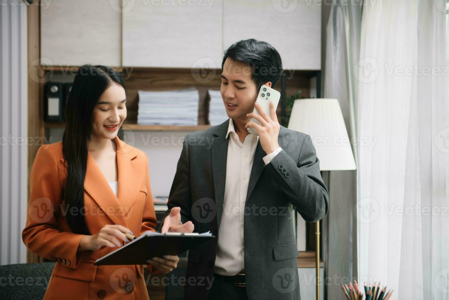 Asian business colleague business presents and explains and using laptop and tablet. Teamwork, financial marketing team,   while sitting in modern office photo