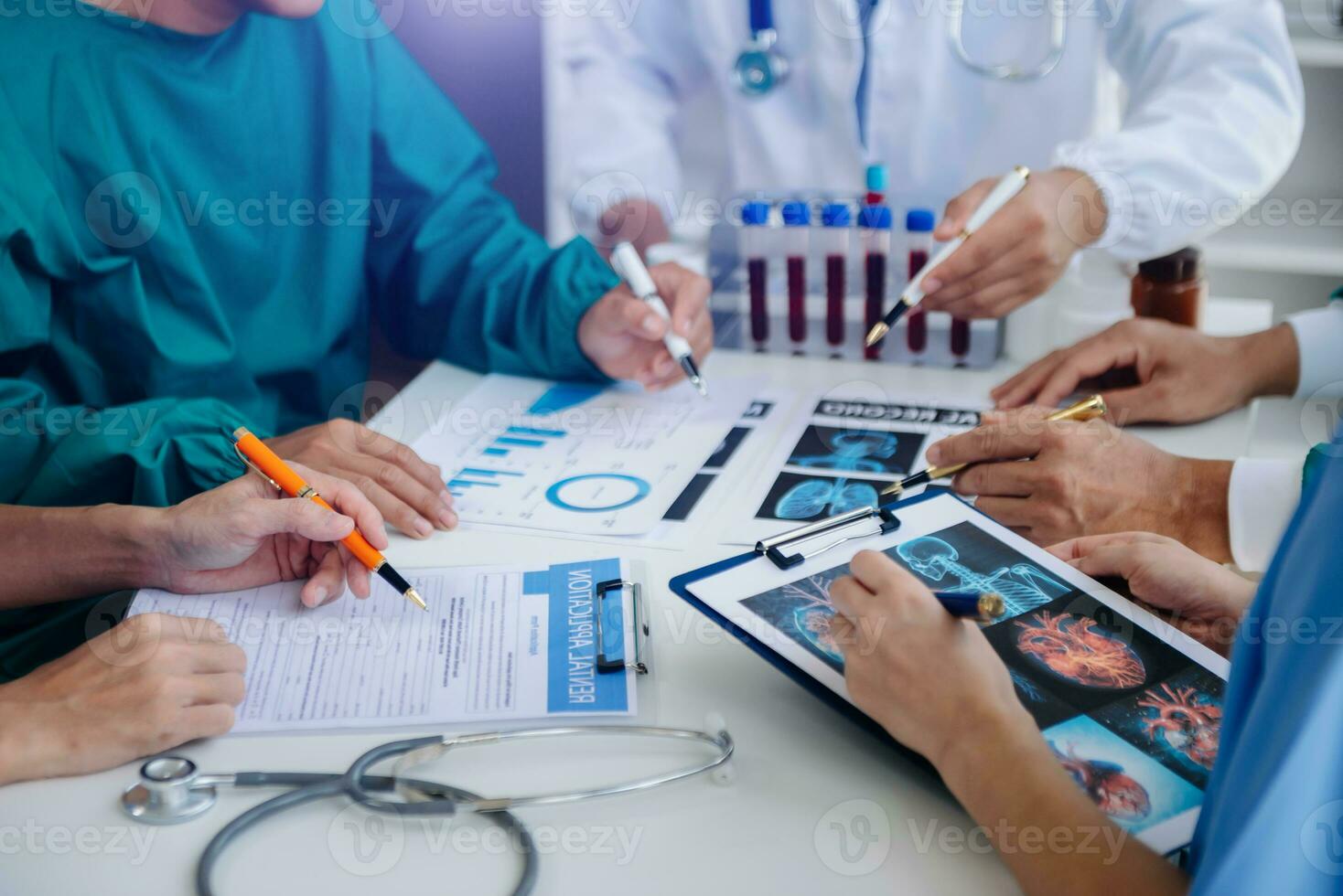 Medical team having a meeting with doctors in white lab coats and surgical scrubs seated at a table discussing a patients working online using computers in the medical industry photo