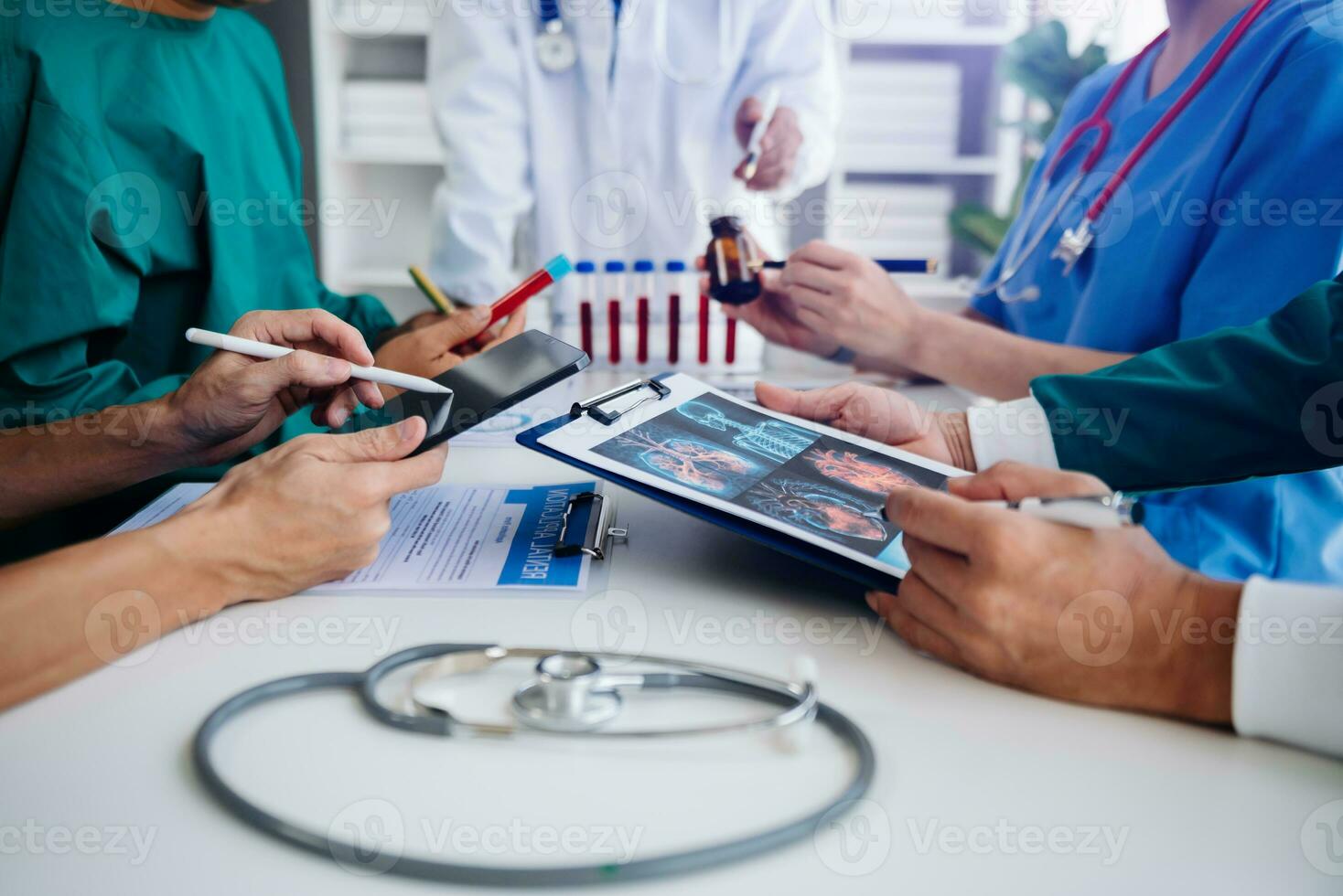 Medical team having a meeting with doctors in white lab coats and surgical scrubs seated at a table discussing a patients working online using computers in the medical industry photo