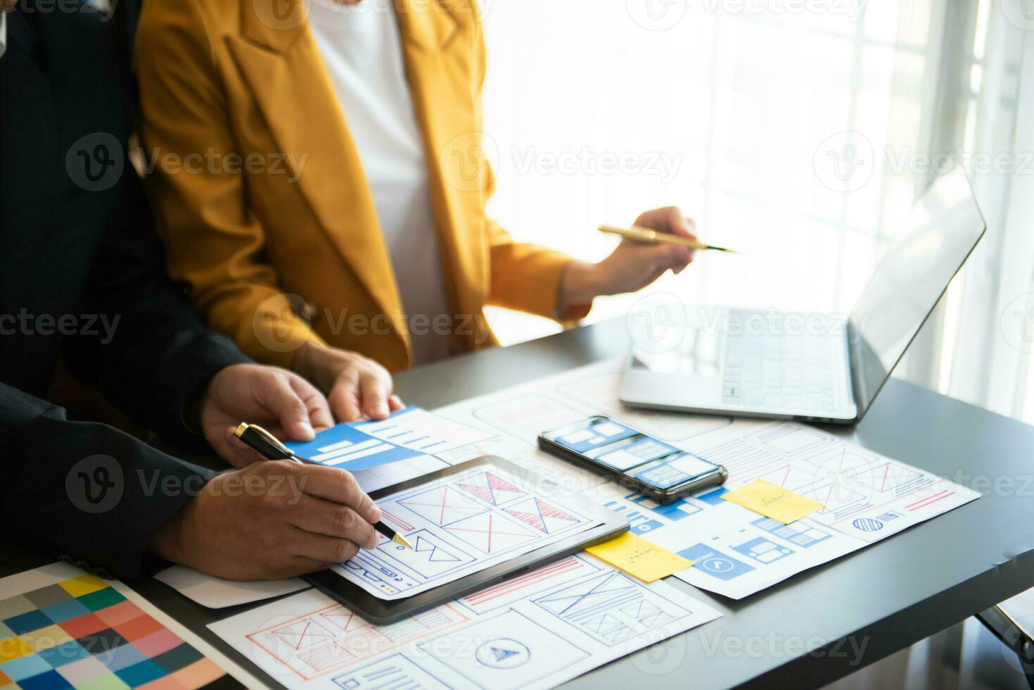 UX developer and ui designer brainstorming about mobile app interface wireframe design with customer breif and color code at office. photo