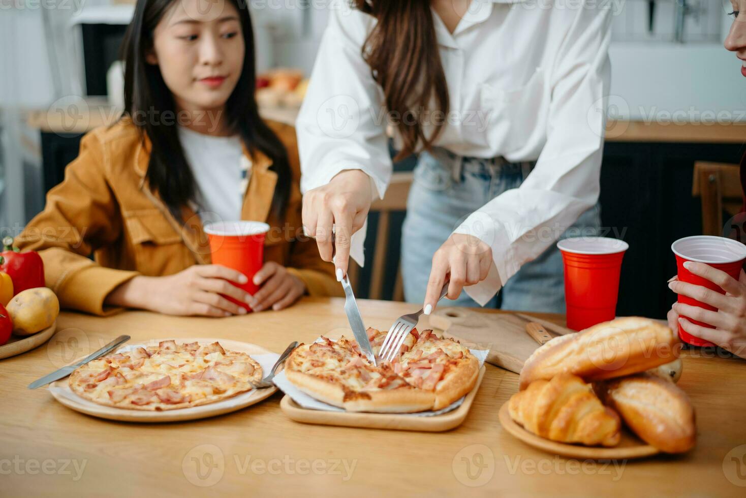 Happy multiracial friends chatting, eating pizza together, having small party at home photo