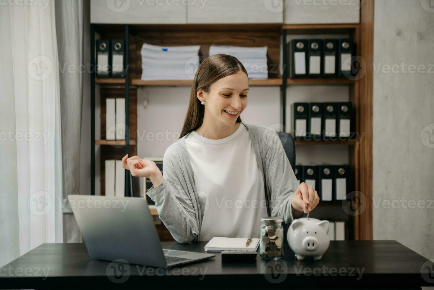 Caucasian Women are putting coins in a piggy bank for a business that grows for profit and saving money for the future. photo