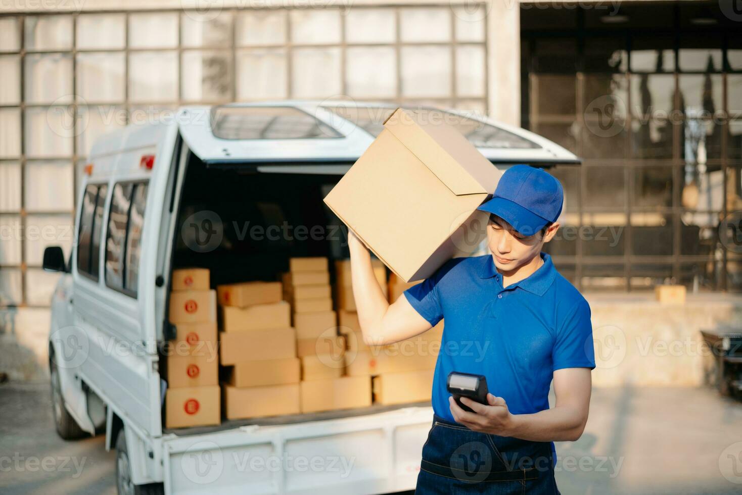 Smiling delivery man standing in front of his van with Holding Box and tablet delivery home and shipping photo