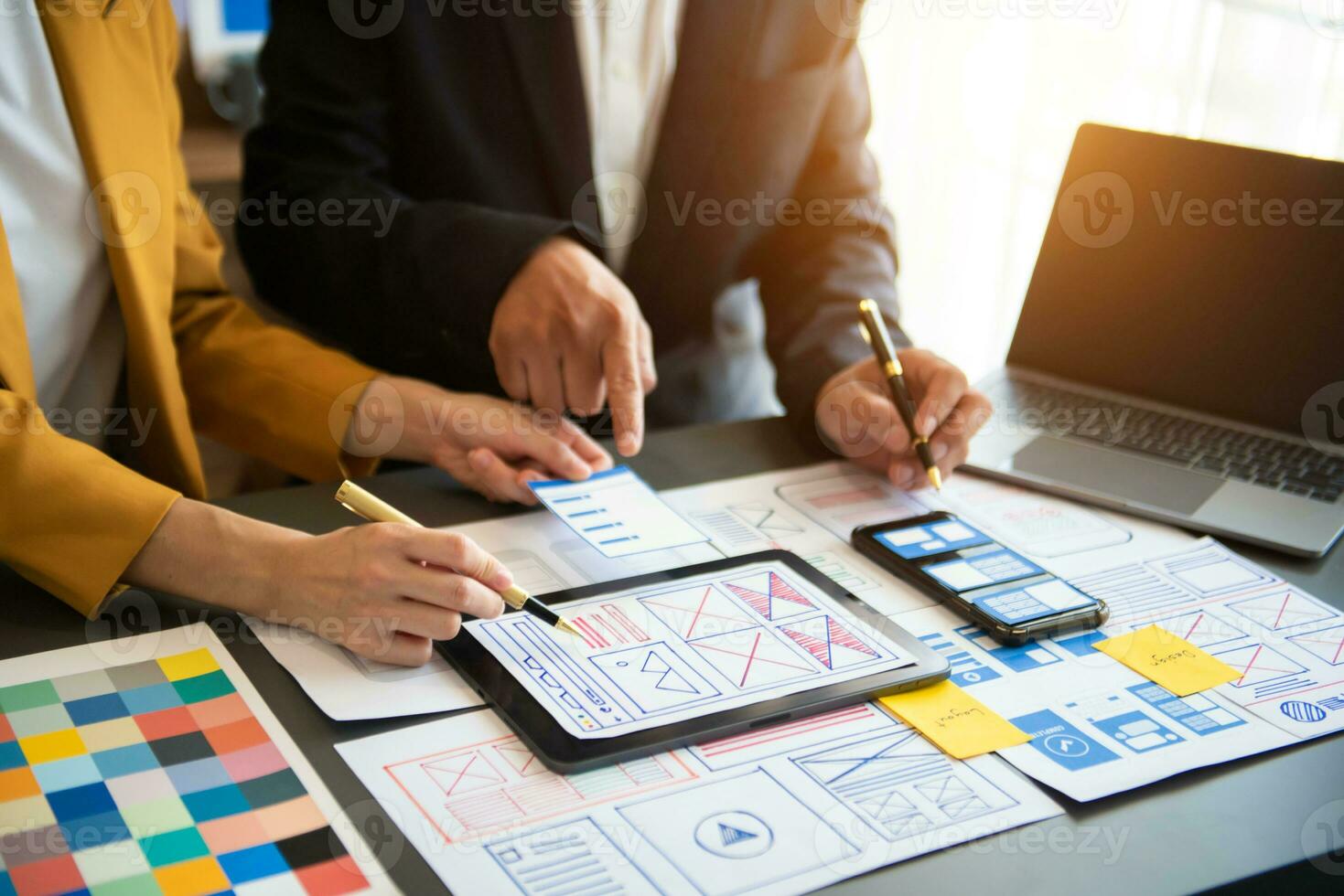 UX developer and ui designer brainstorming about mobile app interface wireframe design with customer breif and color code at office. photo