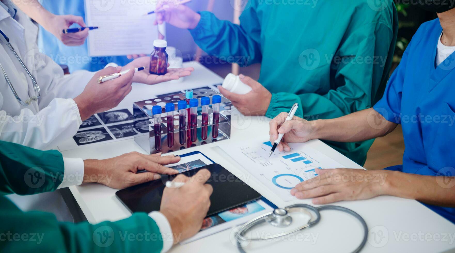 Medical team having a meeting with doctors in white lab coats and surgical scrubs seated at a table discussing a patients working online using computers in the medical industry photo
