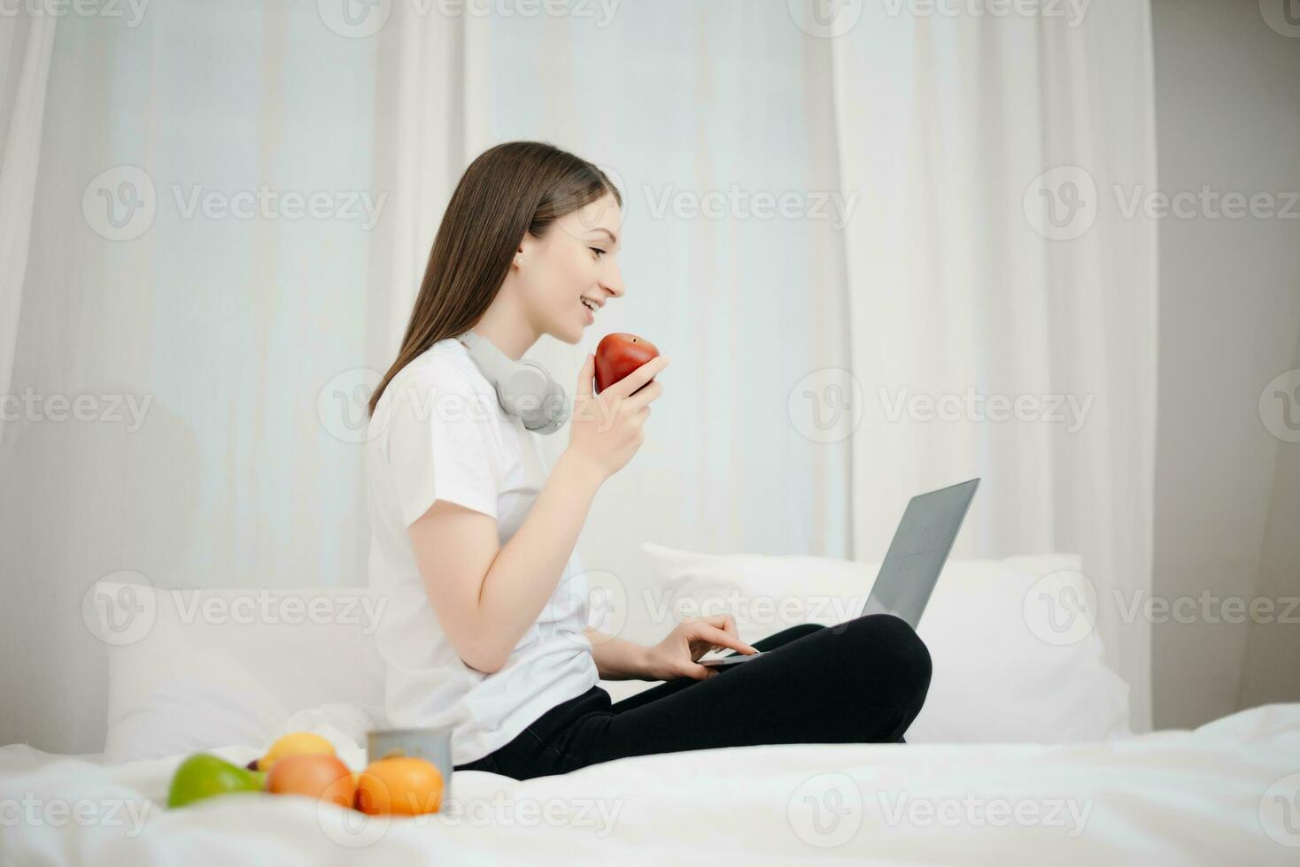 Beautiful young woman on a white bed with coffee cub and using smart phone at home. lifestyle concept photo