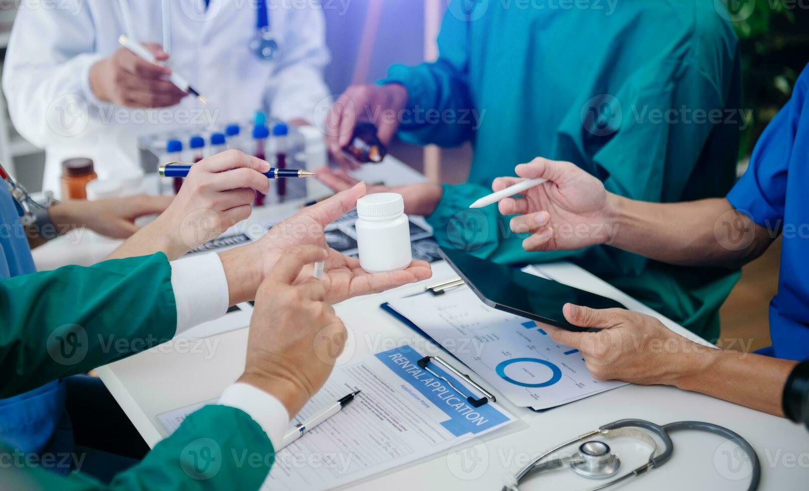 Medical team having a meeting with doctors in white lab coats and surgical scrubs seated at a table discussing a patients working online using computers in the medical industry photo