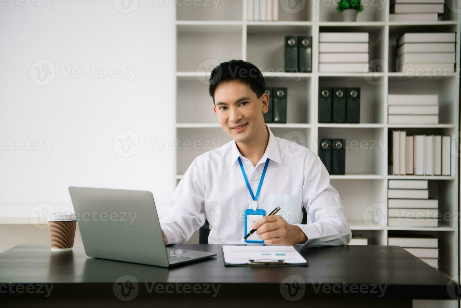 joven asiático negocio hombre utilizando ordenador portátil y tableta mientras sentado a su trabajando lugar. concentrado a trabajar. foto