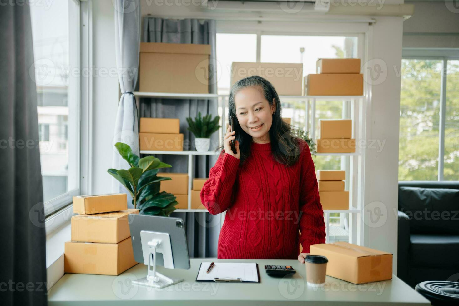 Mature business owner woman prepare parcel box and standing check online orders for deliver to customer on tablet, laptop Shopping Online photo