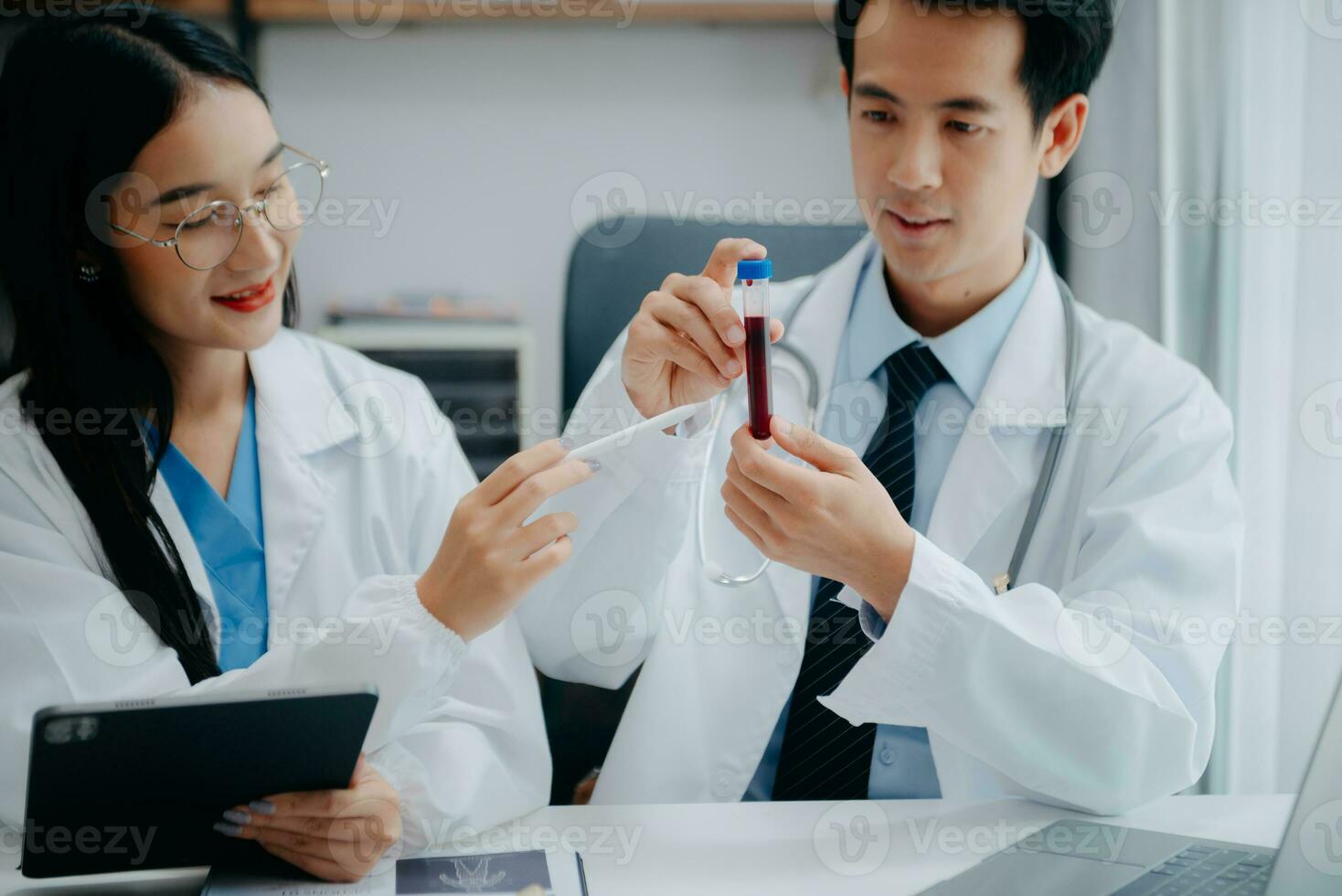 Medical team having a meeting with doctors in white lab coats and surgical scrubs seated at a table discussing a patients working online using computers in the medical industry photo