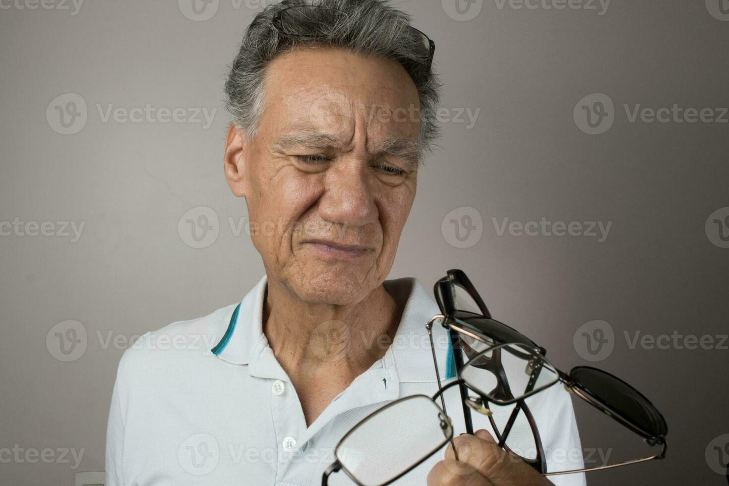 Mature Man checking out and holding up all his old prescription glasses photo