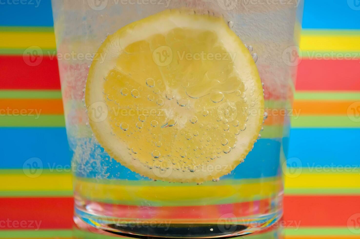 Lemonade fizzy drink in a clear glass with colorful background showing fizzy bubbles photo