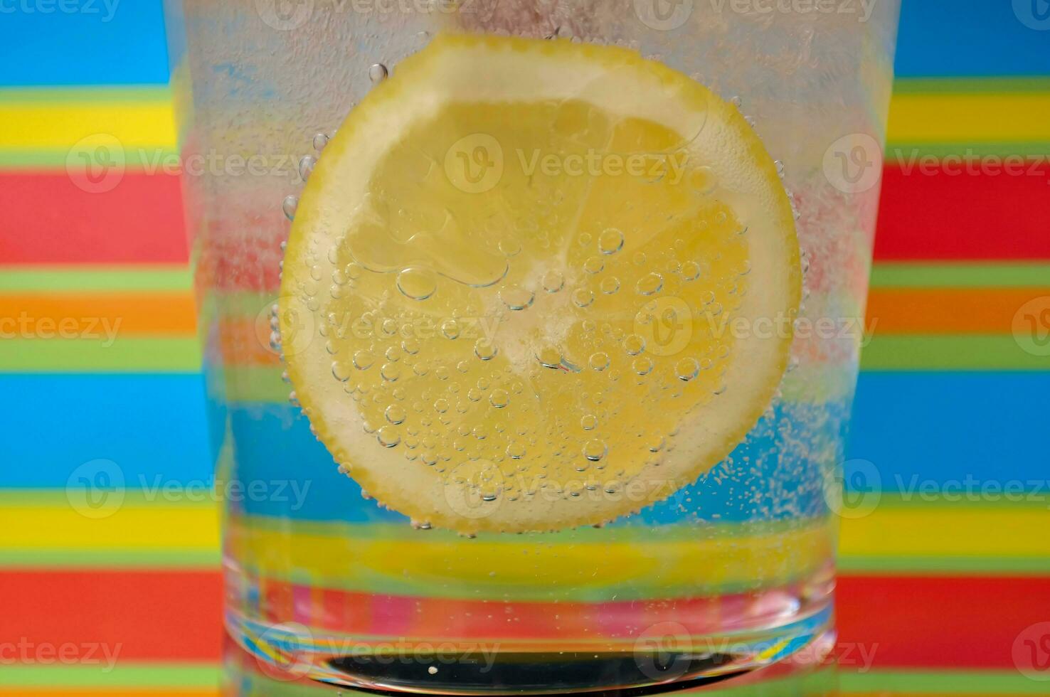 Lemonade fizzy drink in a clear glass with colorful background showing fizzy bubbles photo