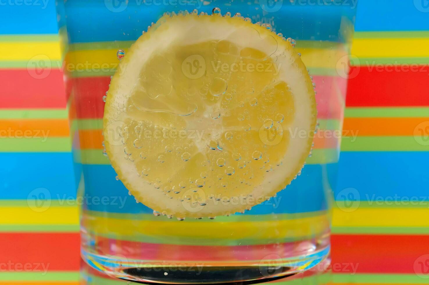 Lemonade fizzy drink in a clear glass with colorful background showing fizzy bubbles photo