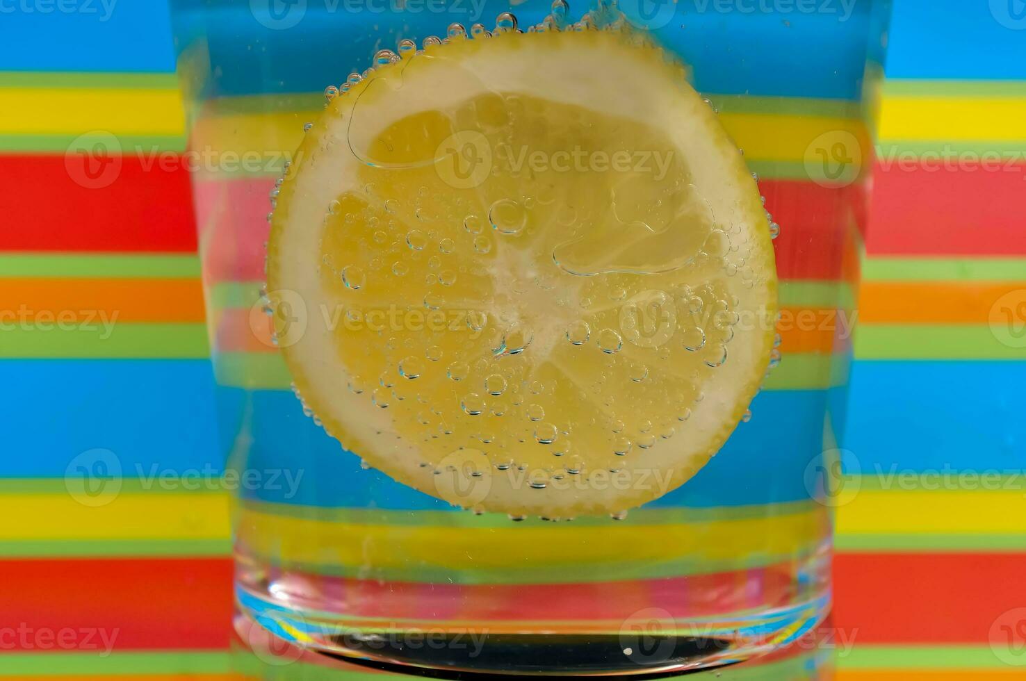 Lemonade fizzy drink in a clear glass with colorful background showing fizzy bubbles photo