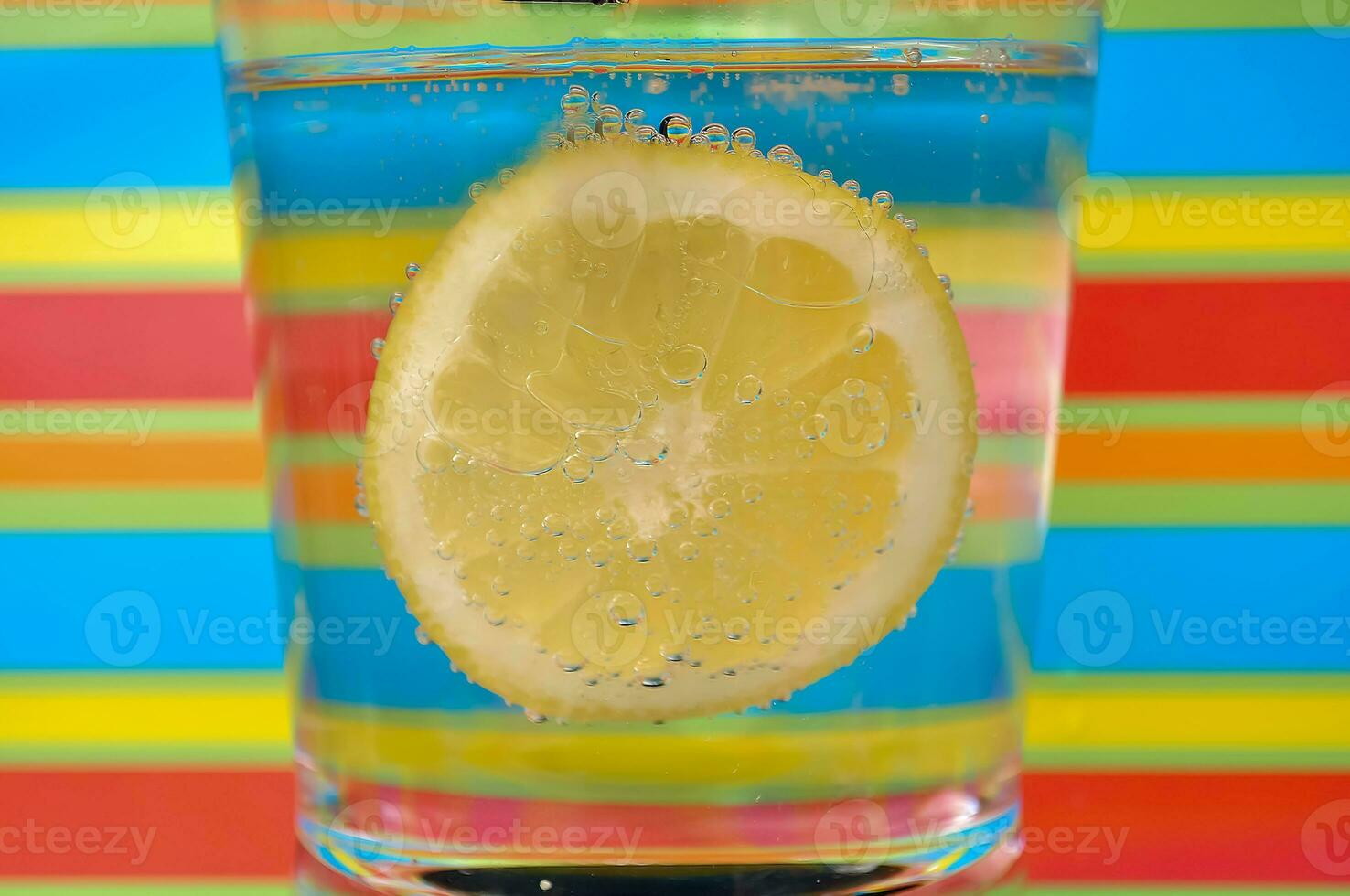 Lemonade fizzy drink in a clear glass with colorful background showing fizzy bubbles photo