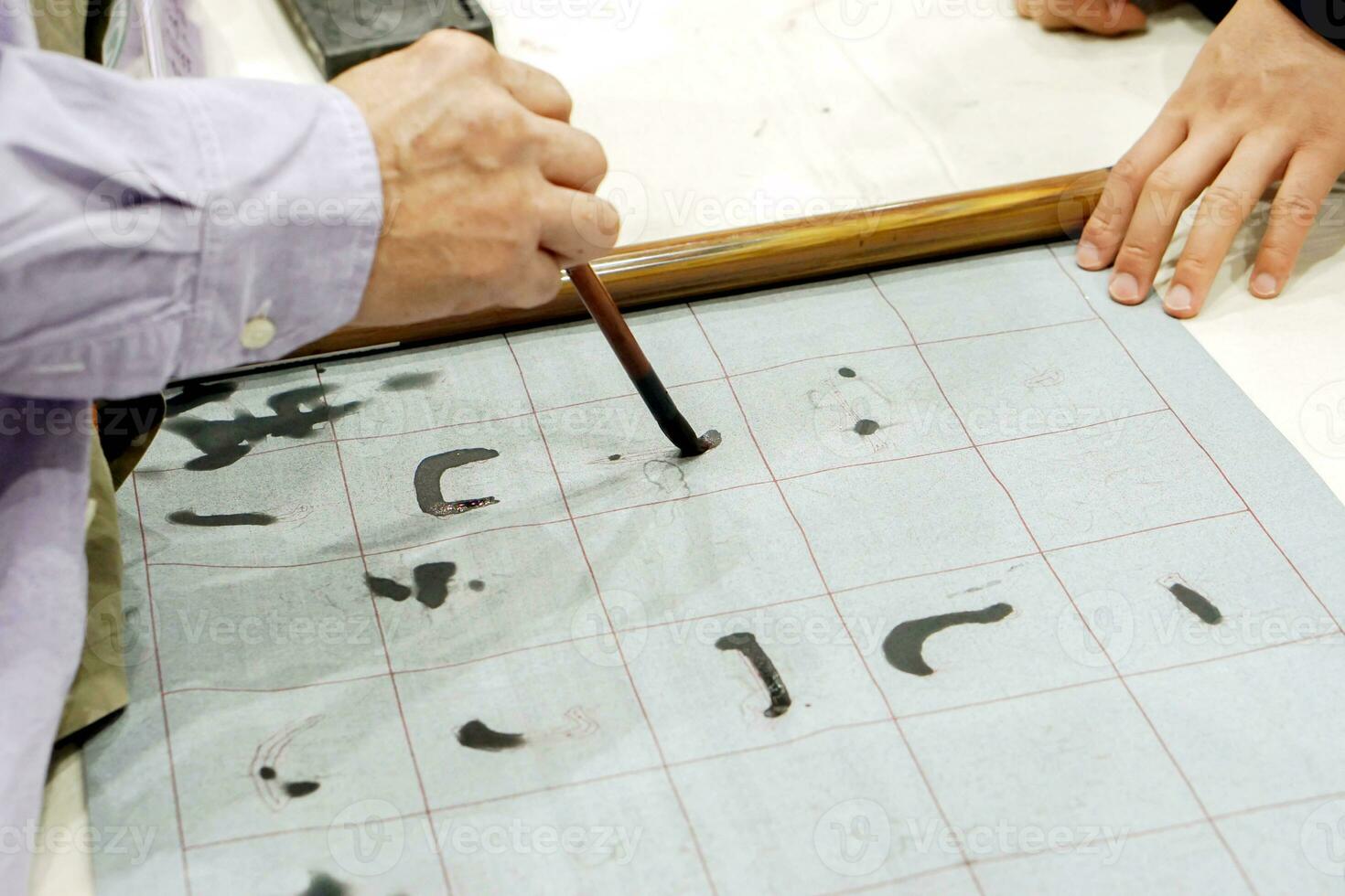 Hand of person holding Chinese brush and demonstration Chinese letters on fabric. photo